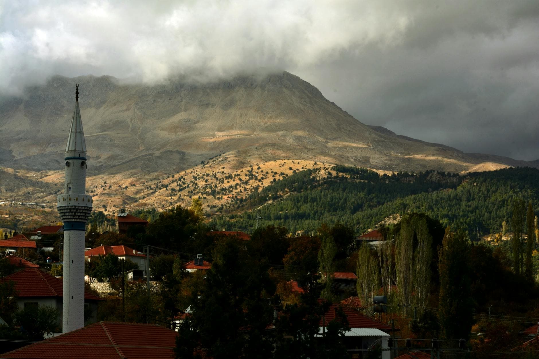 Picturesque landscape of a mosque and mountains under dramatic clouds in Finike, Antalya, Türkiye.