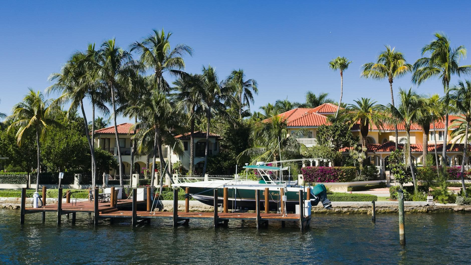 Scenic view of luxury waterfront homes with palm trees and a boat docked in Fort Lauderdale, Florida.