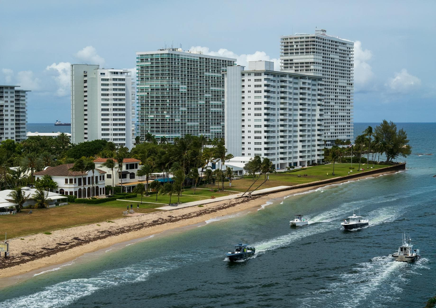 Aerial view of Fort Lauderdale high-rise buildings along the beach with boats on the water, exemplifying coastal city life.