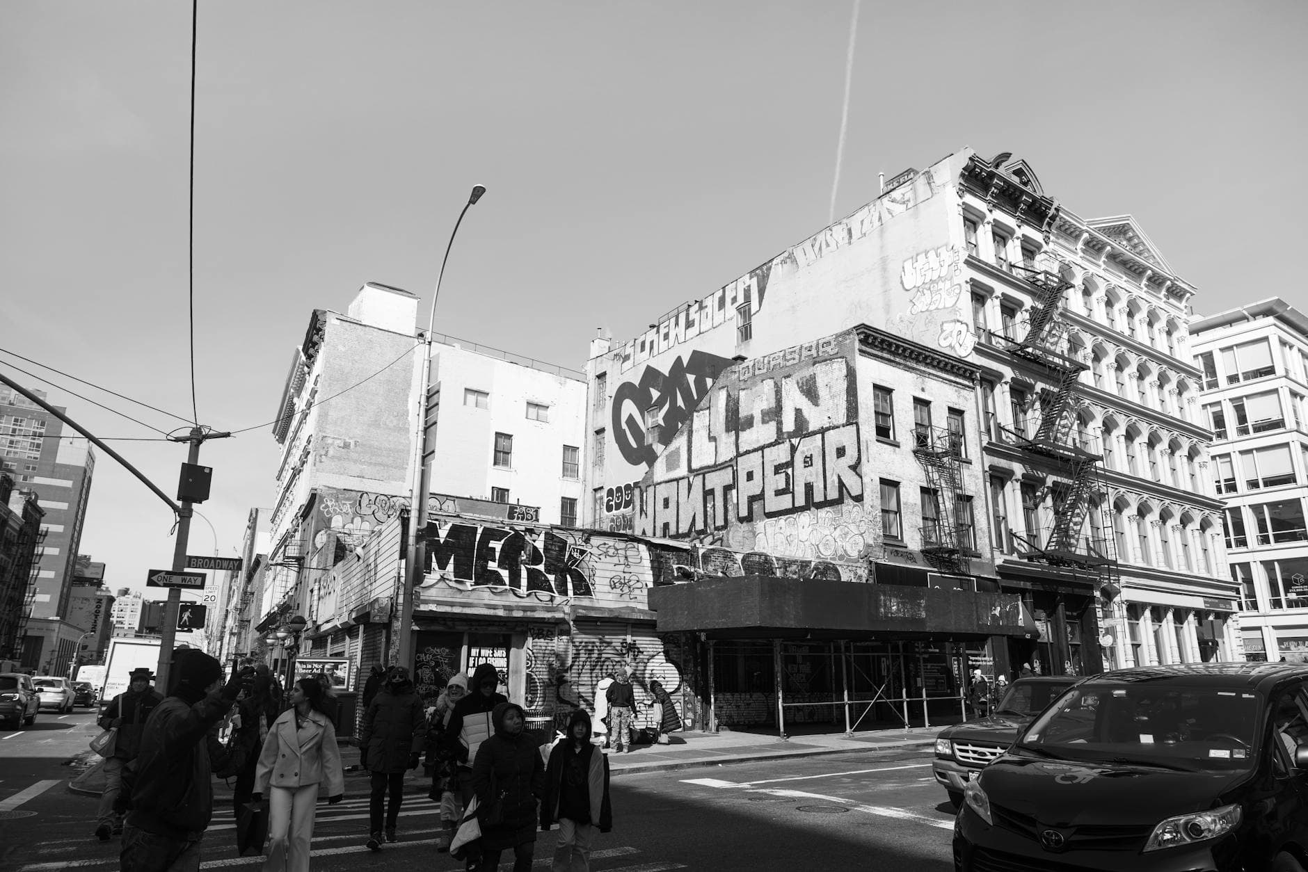 Black and white street view with graffiti-covered buildings and people walking.