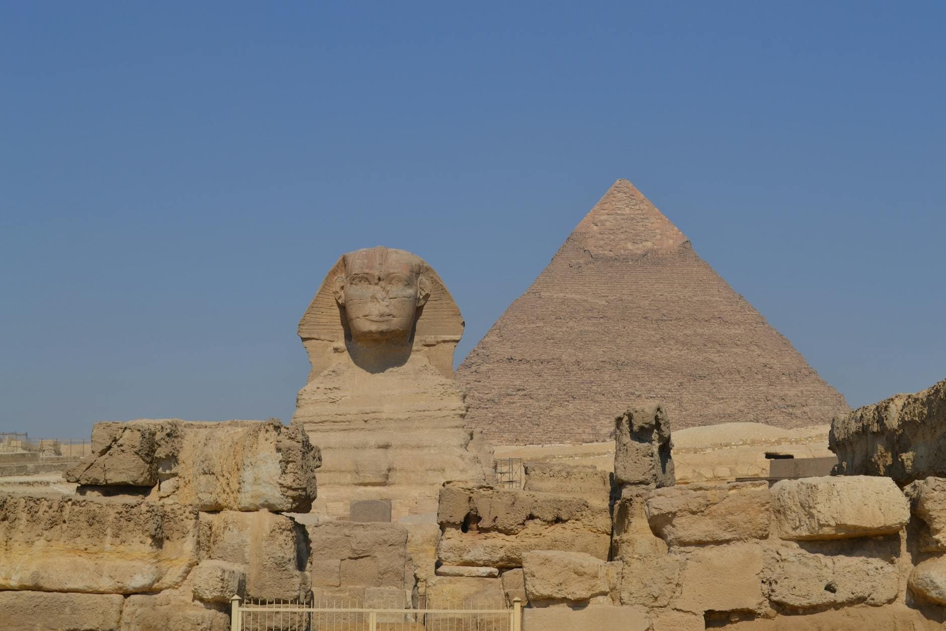View of the Great Sphinx and Pyramid of Giza under clear blue skies in Egypt.