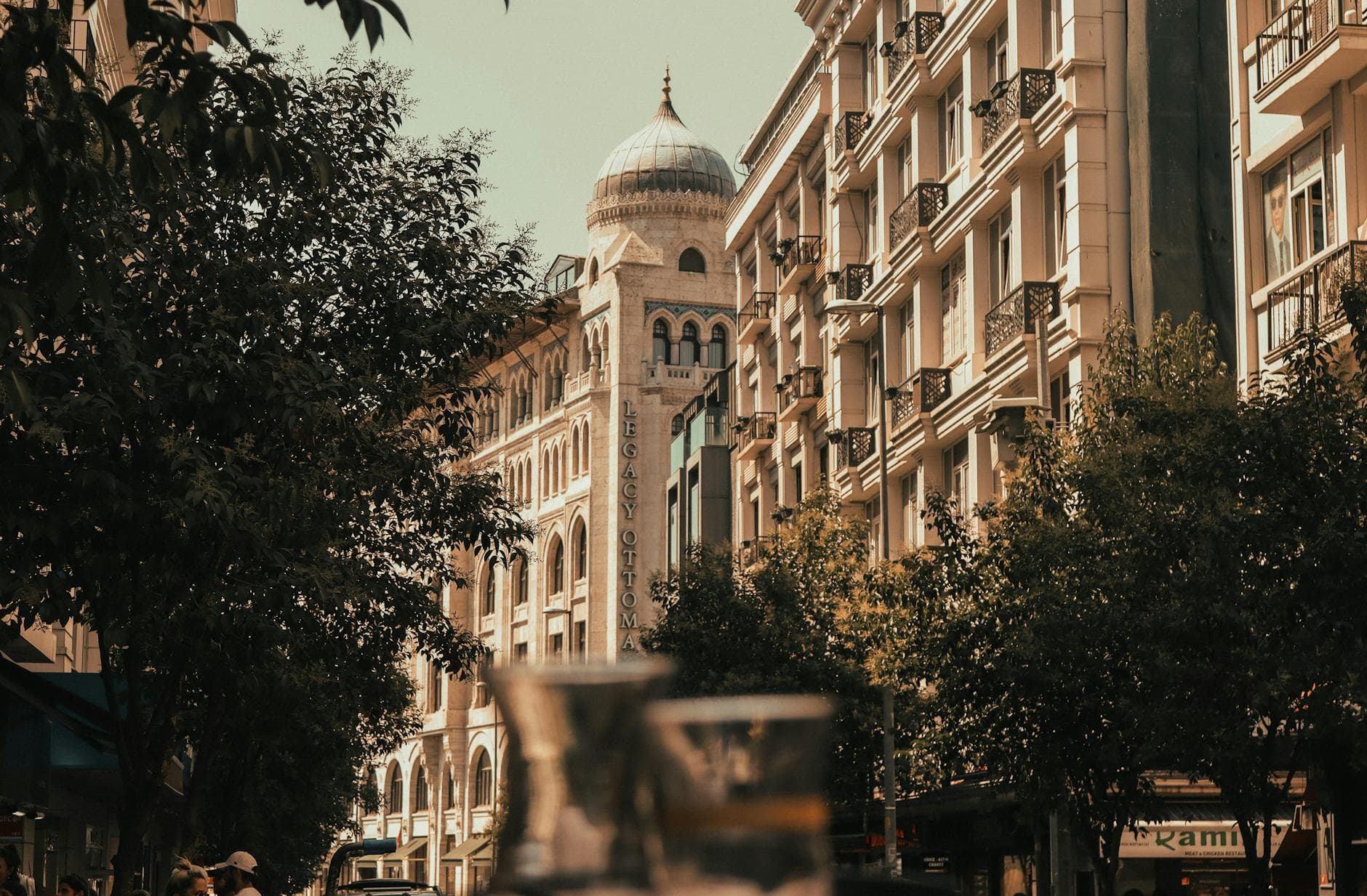 View of Istanbul street with Legacy Ottoman Hotel, featuring urban architecture and city life vibes.
