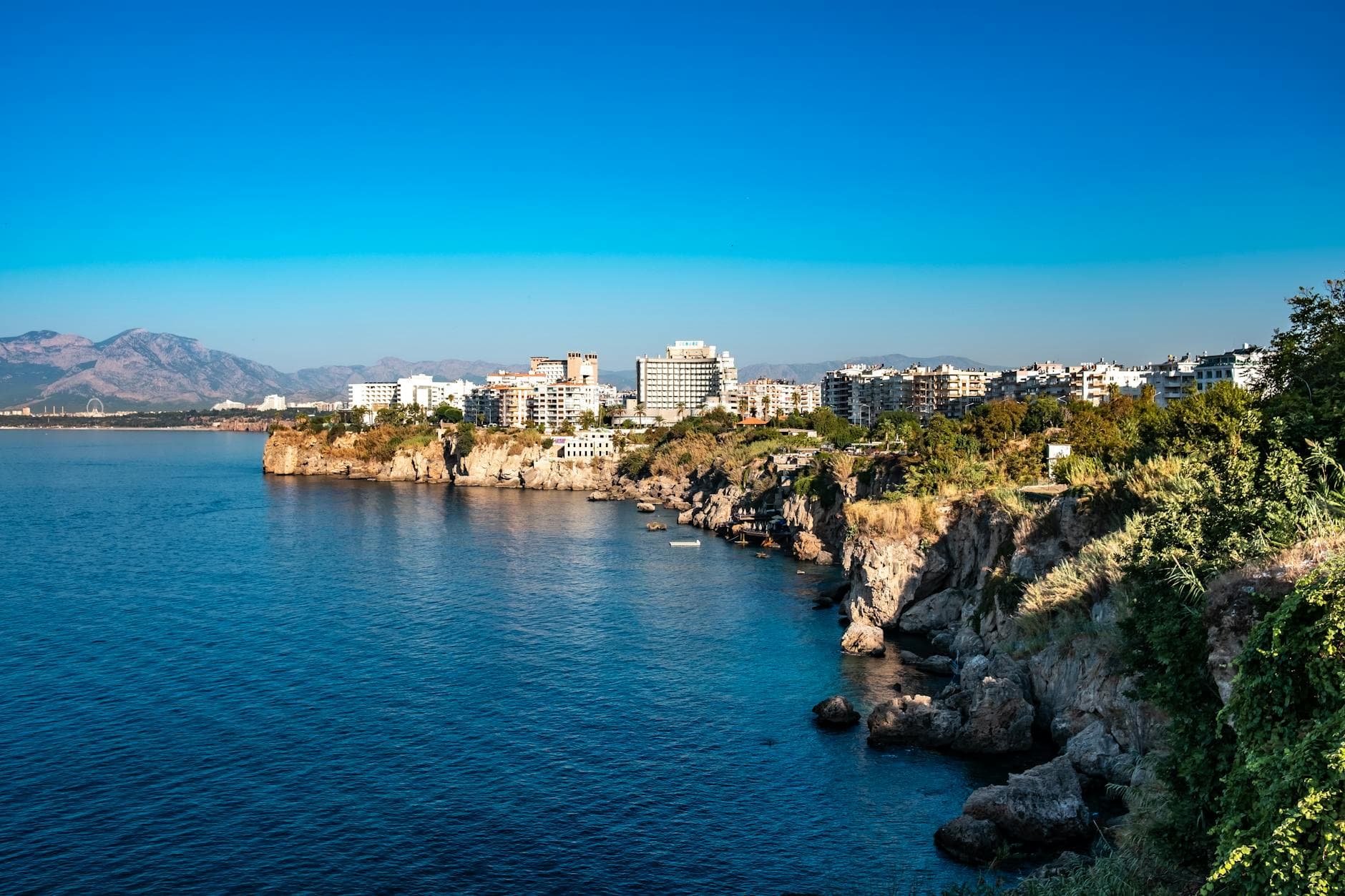 Beautiful coastal cityscape of Antalya, Türkiye featuring cliffs and serene sea under clear blue skies.