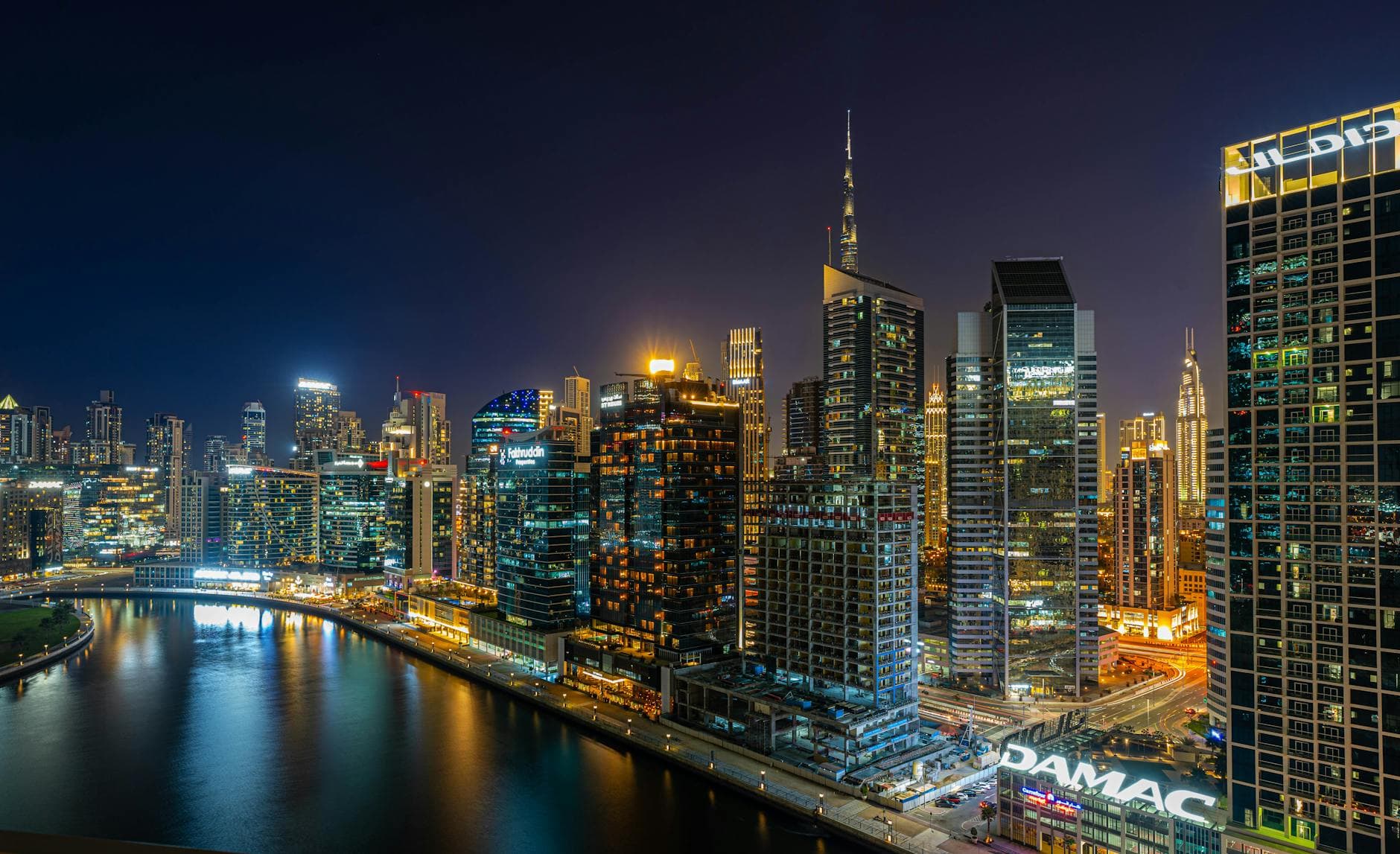 Stunning aerial view of Dubai's illuminated skyline at night, featuring modern skyscrapers along the water.