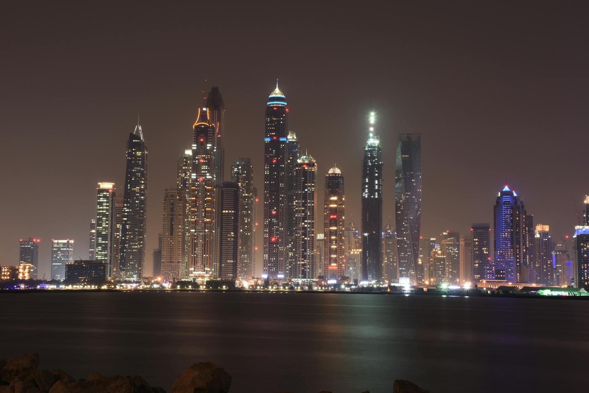 A captivating nighttime view of Dubai's illuminated skyline with reflection on the waterfront.