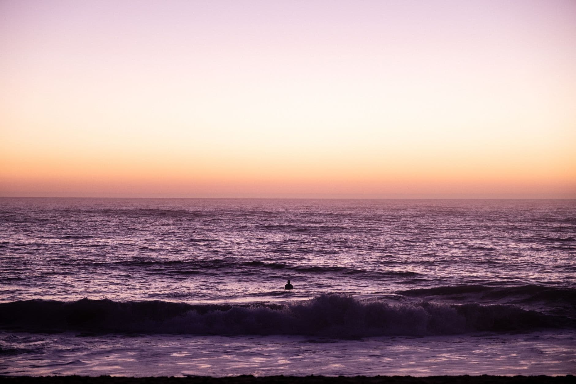 Silhouetted person watching a stunning sunset over the Atlantic Ocean in Hossegor, France.