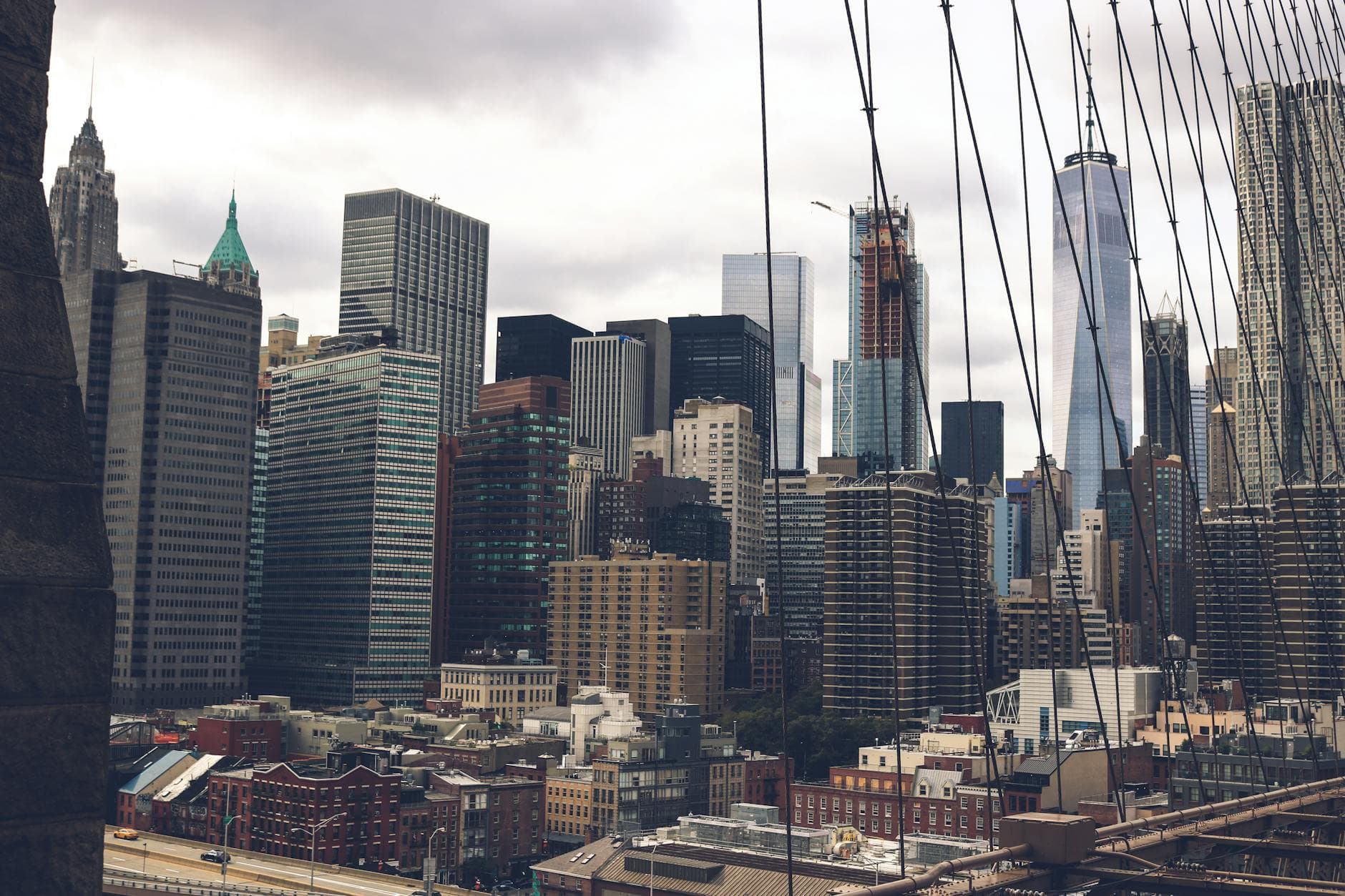A dramatic view of the skyscrapers of New York City captured from the Brooklyn Bridge.