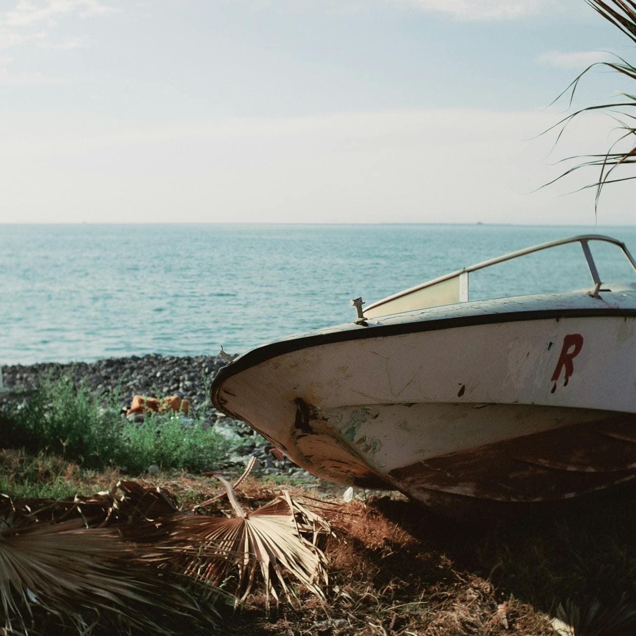 A weathered boat sits on the coast of İskenderun, Türkiye, overlooking the sea.