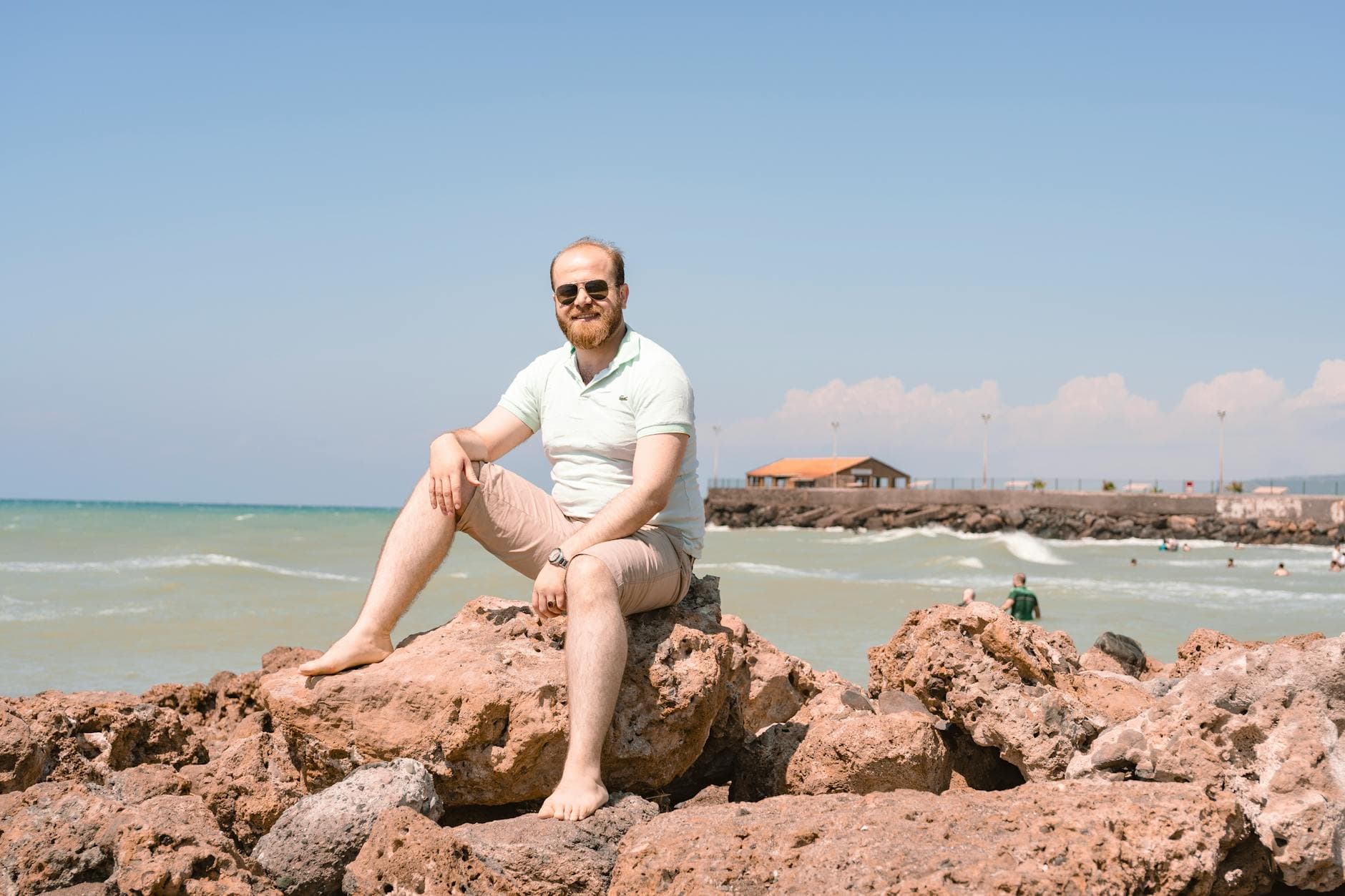A man sits on rocky beach with sunglasses enjoying the view in İskenderun, Turkey.
