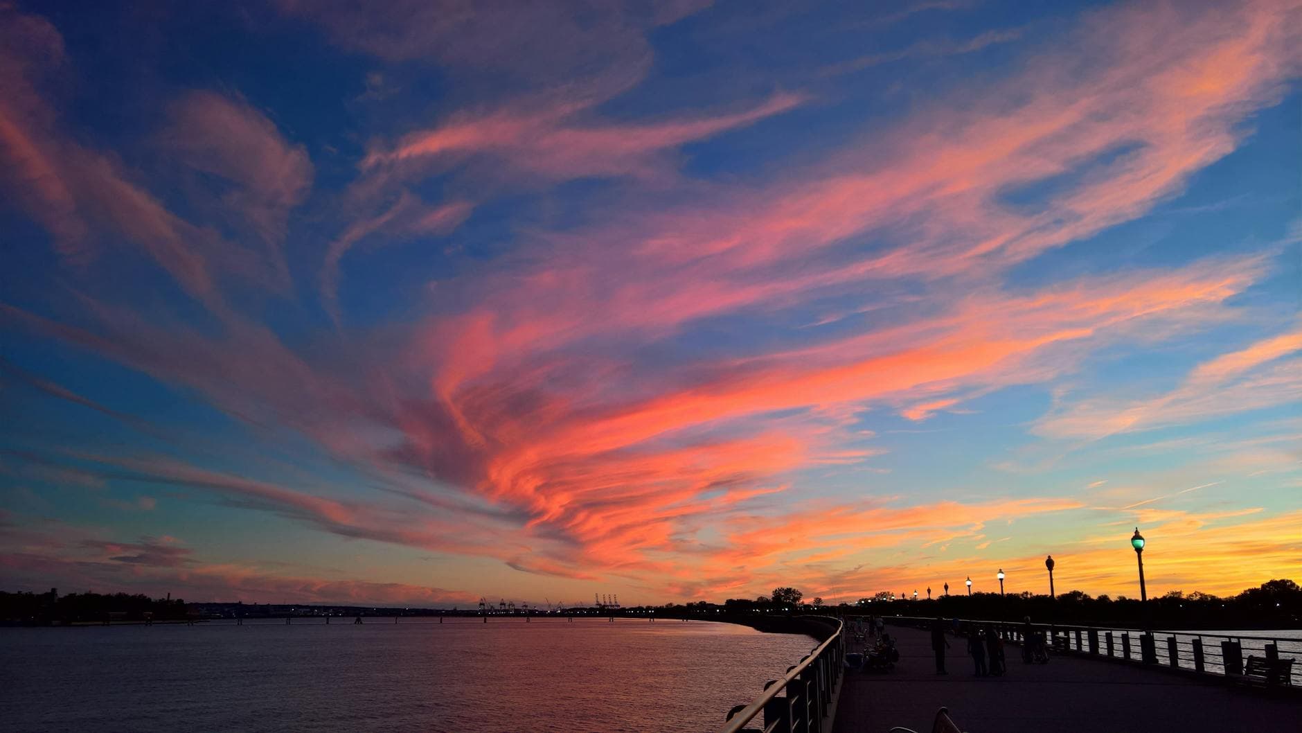 Stunning scenic view of a vibrant sunset over the Jersey City waterfront featuring colorful clouds and a calm river.