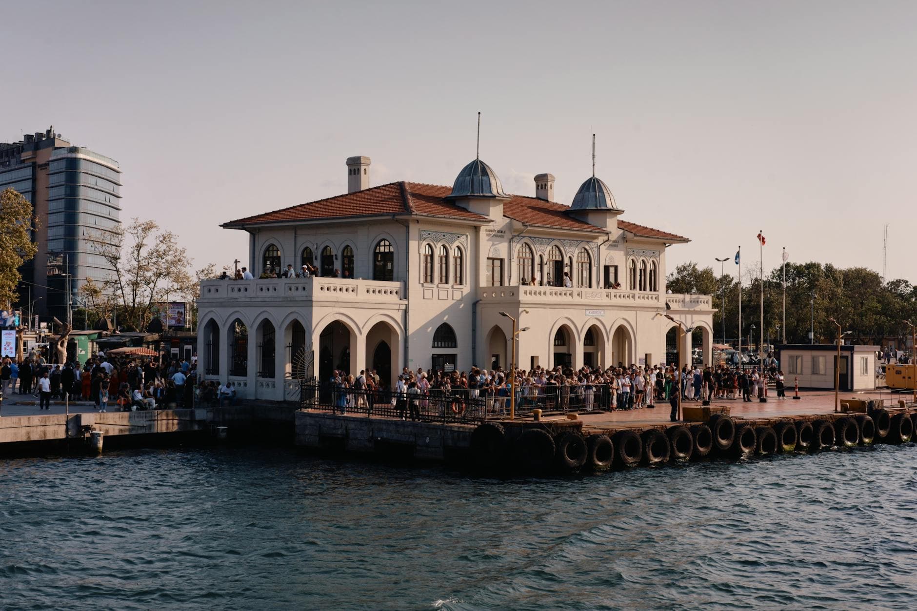 Captivating view of a historic seaside building in İstanbul, Türkiye, bustling with people.