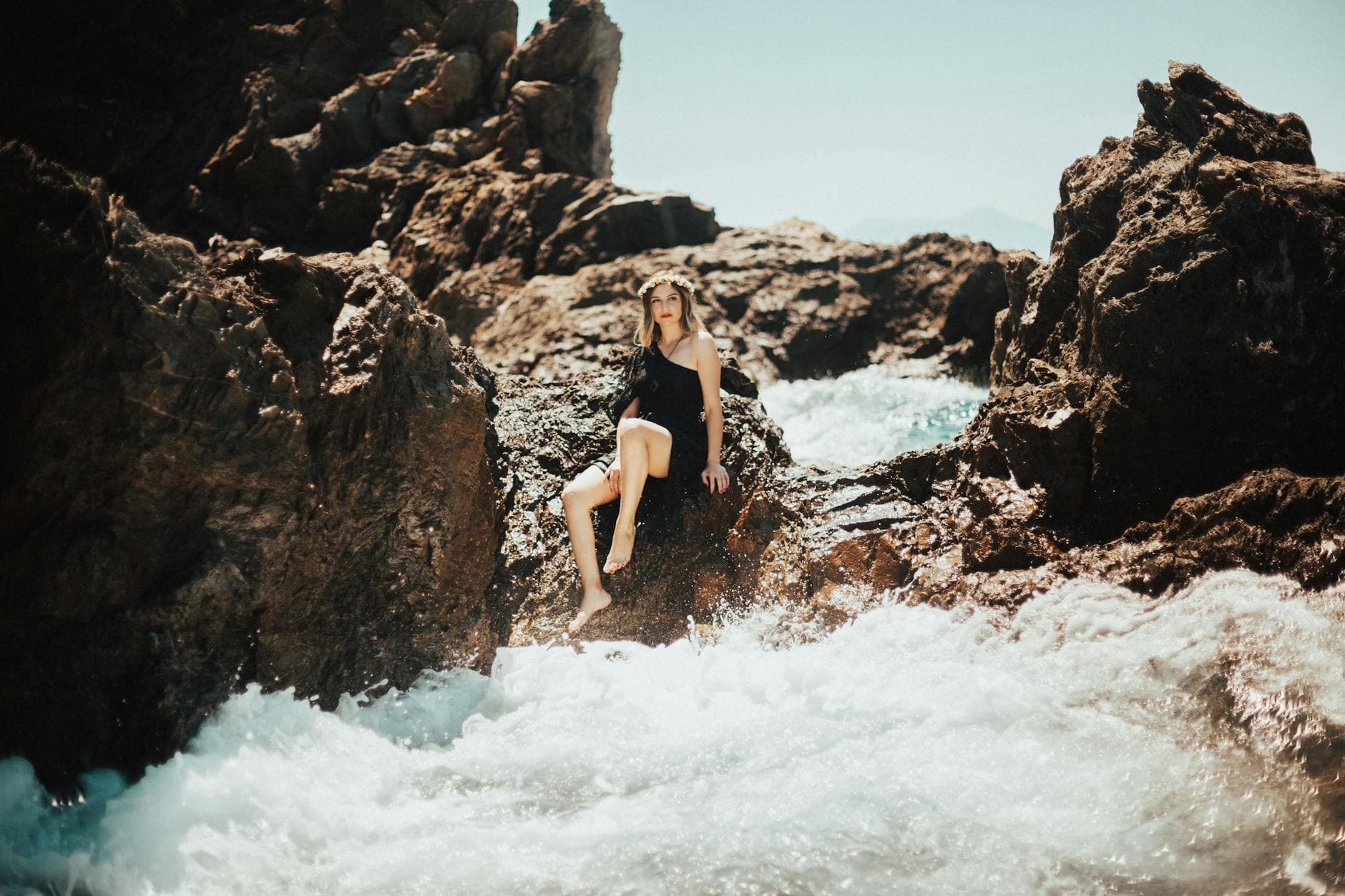 Woman in black dress posing on a rocky beach in Karaburun, Turkey.