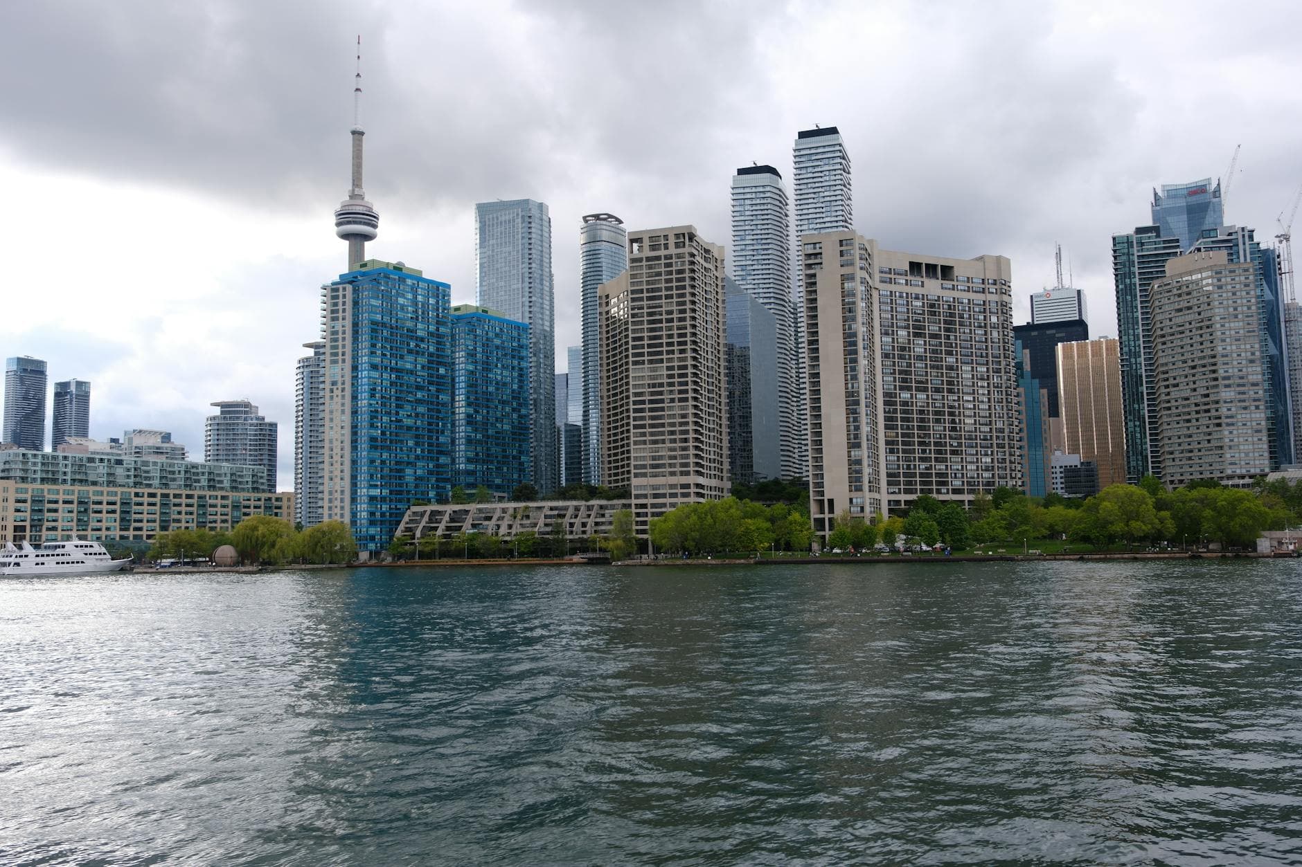 Toronto's skyline featuring the iconic CN Tower and modern skyscrapers across the waterfront under cloudy skies.