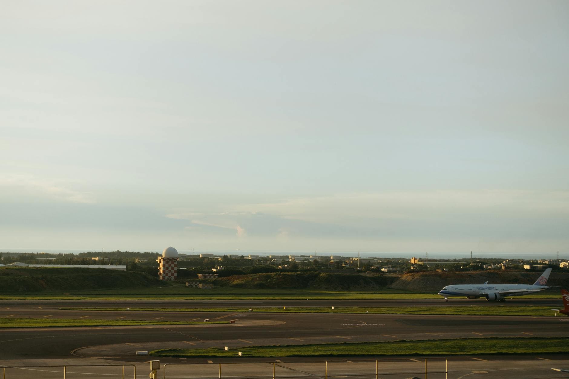An airplane on the runway during sunset with a distant cityscape view.