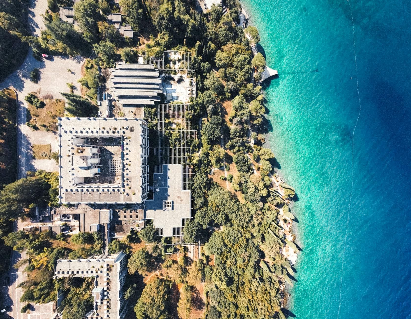 Drone shot of Haludovo Hotel ruins on Krk Island, Croatia, showcasing the coastline and clear blue sea.
