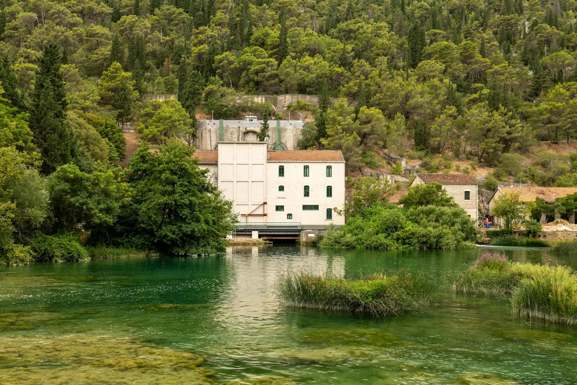 Historic building surrounded by lush greenery over the Krka River in Šibensko-kninska županija, Croatia.