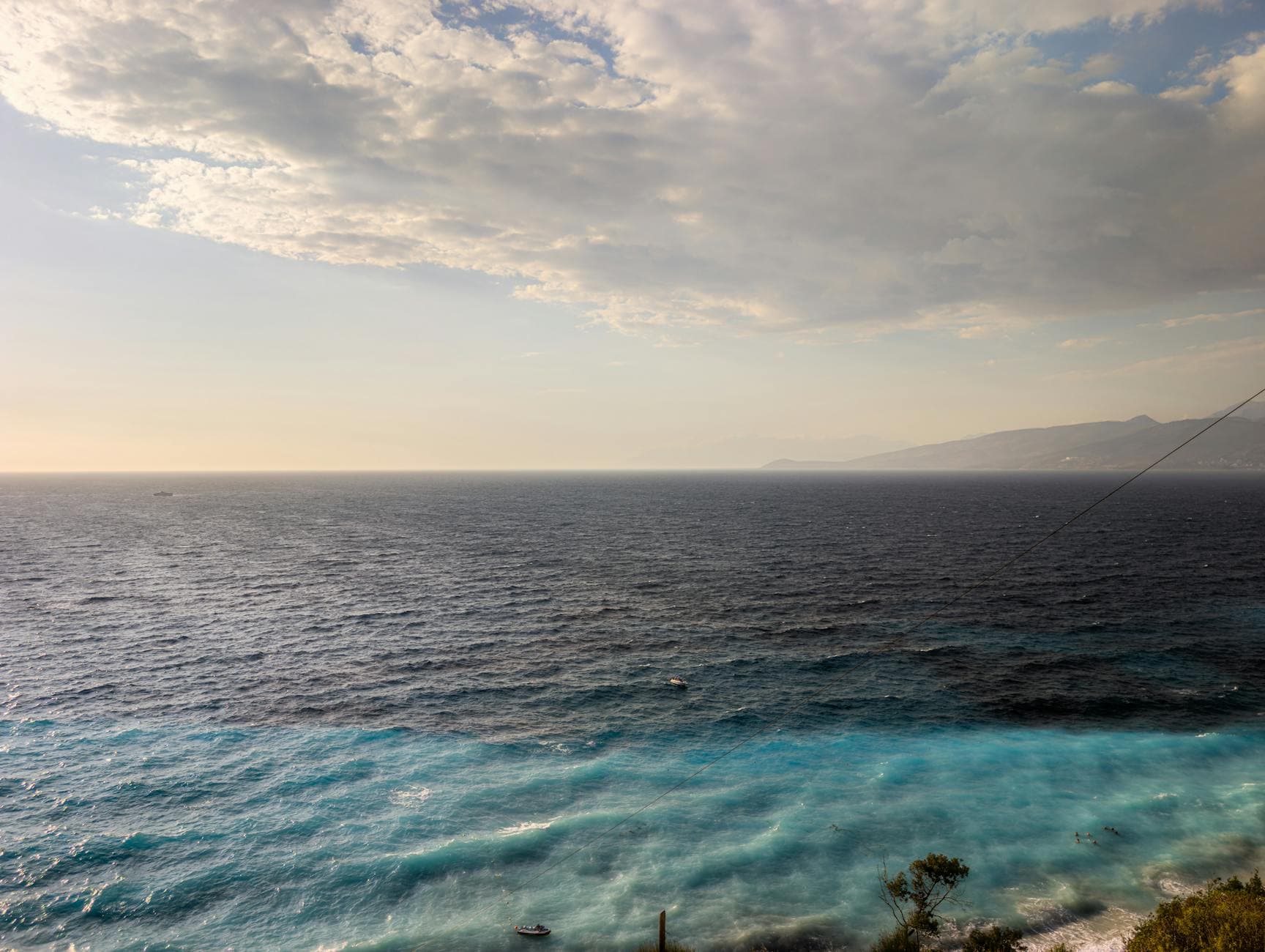 Serene seascape of Ksamil beach in Vlorë County, Albania with turquoise waters under a partly cloudy sky.