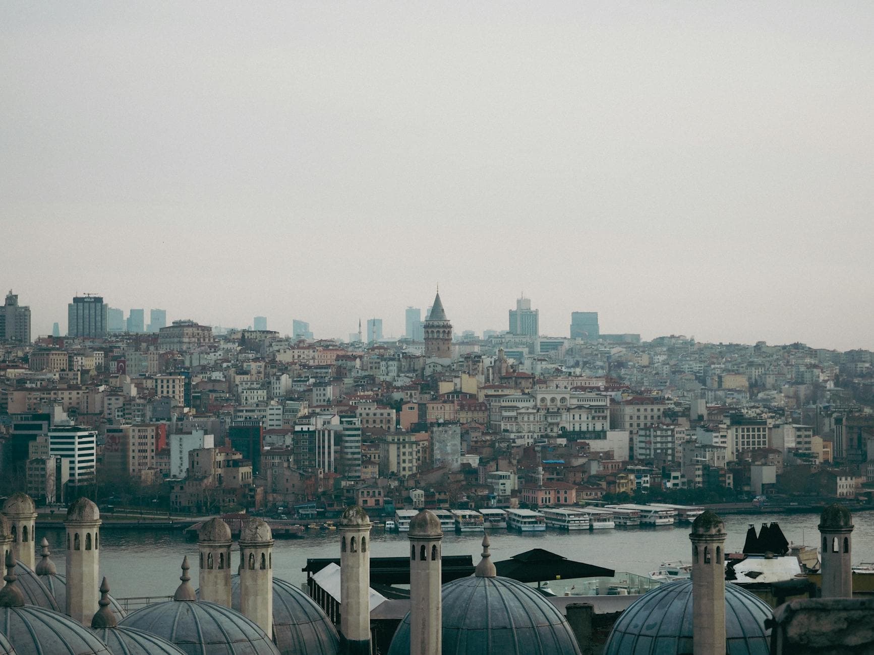 A panoramic view of Istanbul with the iconic Galata Tower surrounded by buildings and domes along the waterfront.