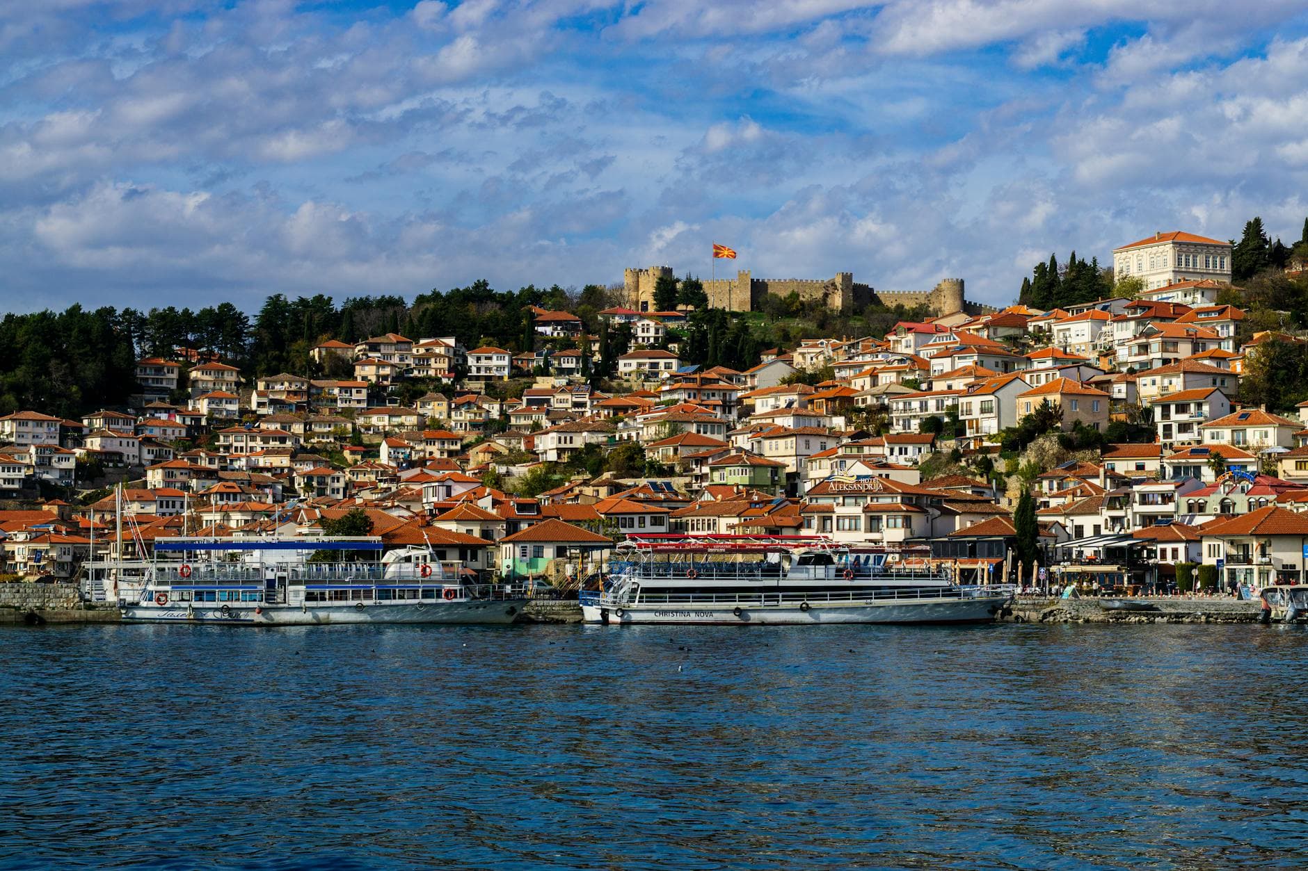 Beautiful panoramic view of Ohrid's red-roofed houses and Lake Ohrid, with Samuil's Fortress in the background.