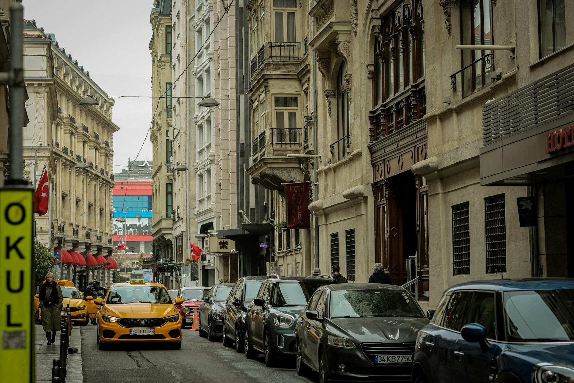 Street view of Istanbul featuring classic architecture, parked cars, and vibrant city life.