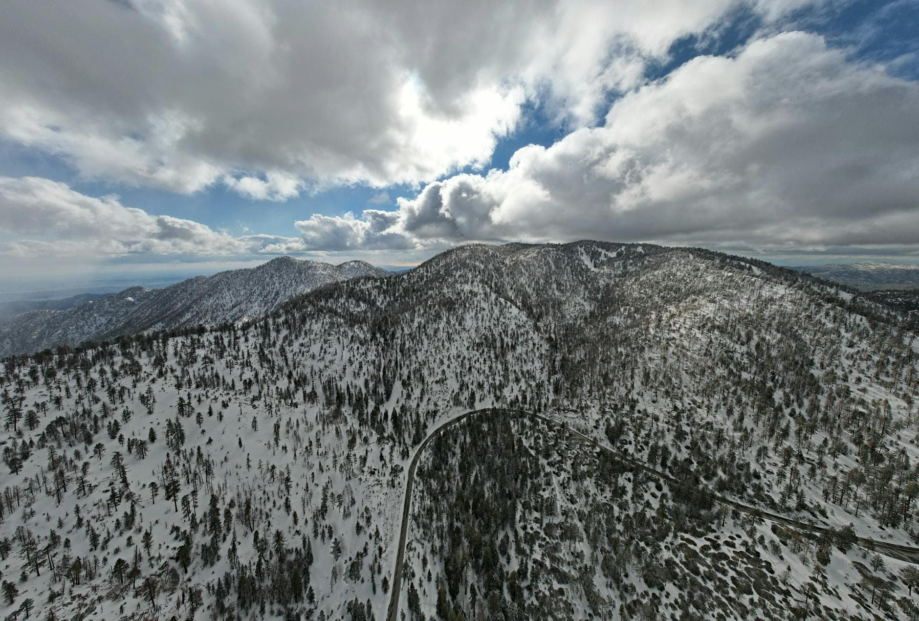 A breathtaking aerial view of snowy mountain peaks under a dramatic cloudy sky in La Cañada Flintridge.