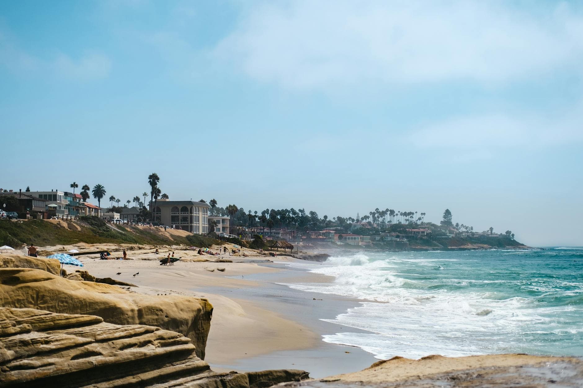 Beautiful seaside view of La Jolla Shores with waves, sand, and coastal homes in the background.