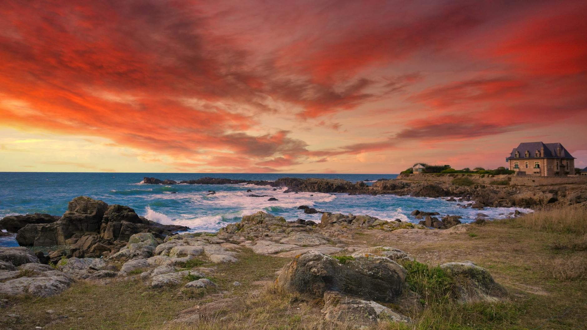 Experience the vibrant sunset over the rocky shores of La Baule, France. A breathtaking coastal view.