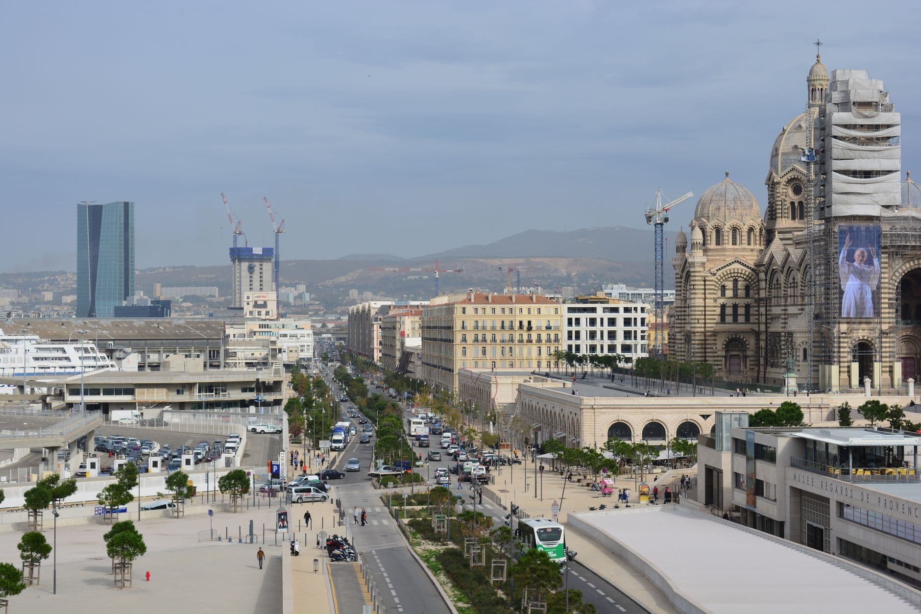 A bustling urban scene in Marseille featuring the iconic cathedral and busy streets.