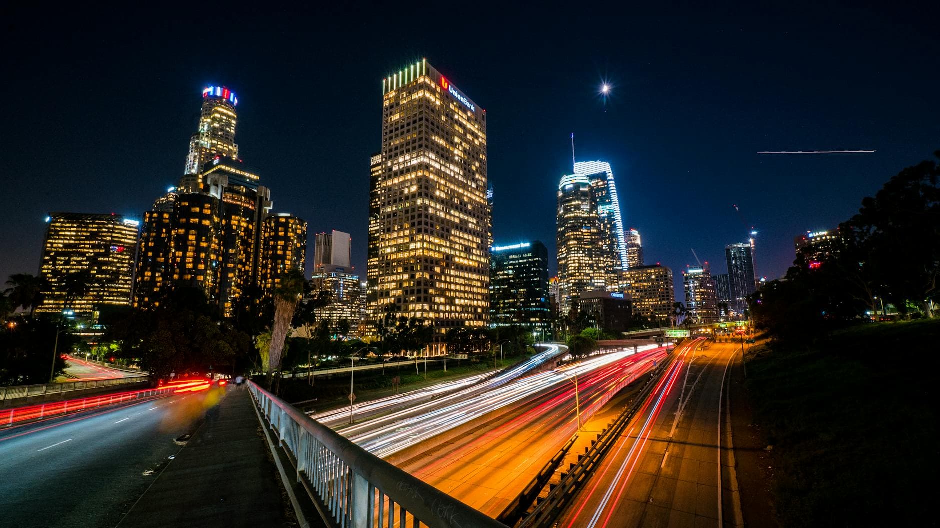 A stunning night view of downtown Los Angeles featuring illuminated skyscrapers and colorful traffic trails, capturing urban life.