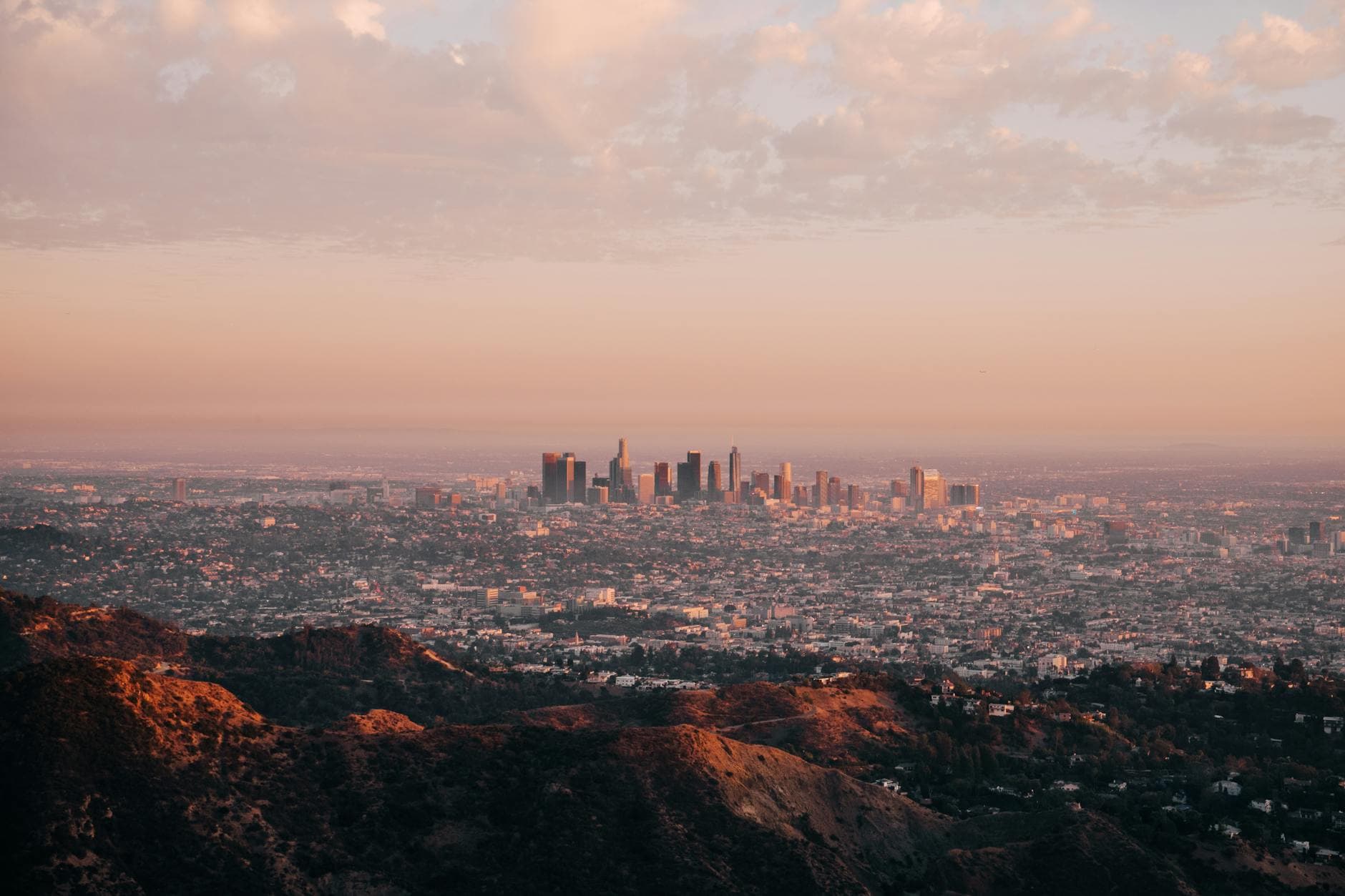 Aerial view of Los Angeles skyline during sunset with hills in the foreground.