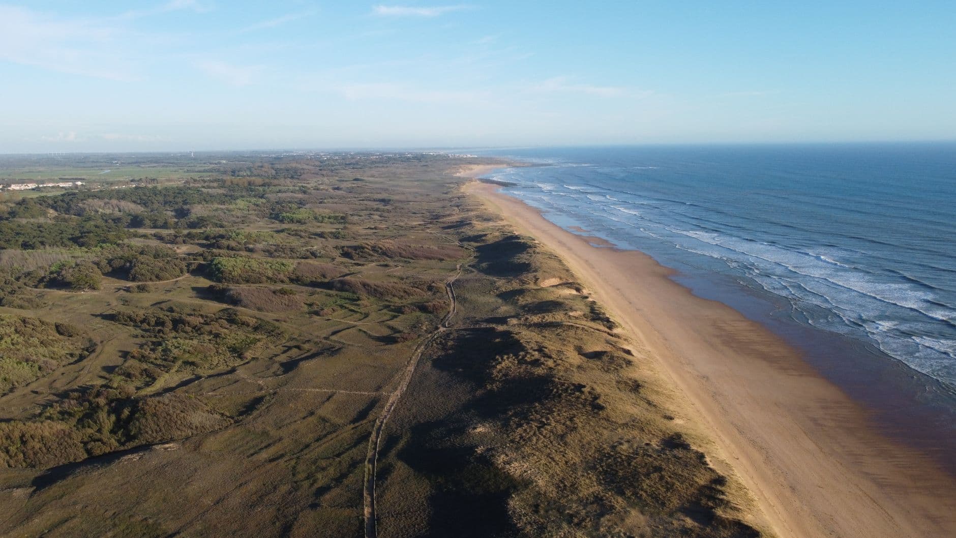 Aerial shot of the Saint-Gilles-Croix-de-Vie coastline in Pays de la Loire, France, featuring waves meeting sandy shores.