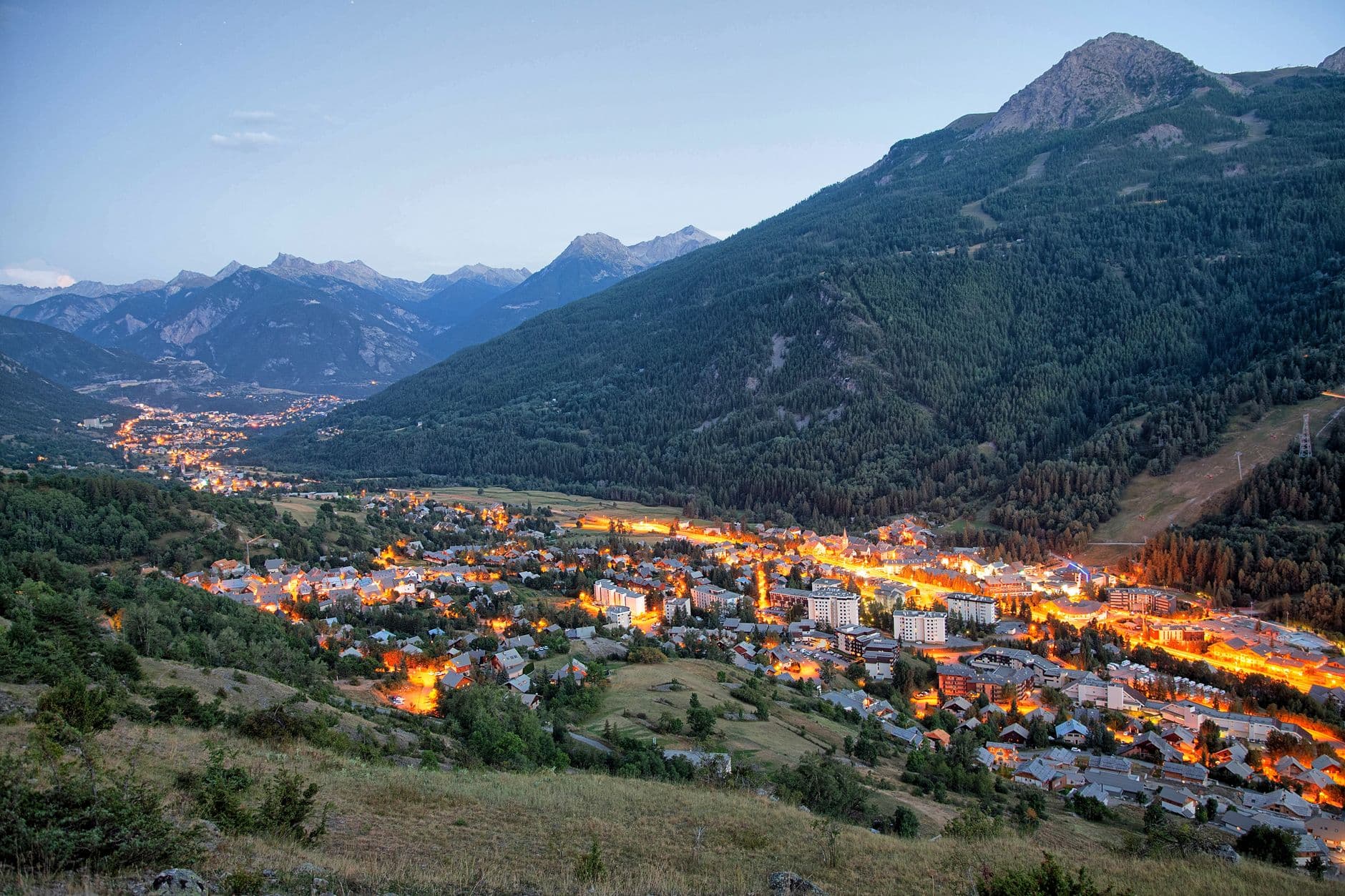 A breathtaking aerial view of La Salle-les-Alpes, France, illuminated at twilight, surrounded by majestic mountains.