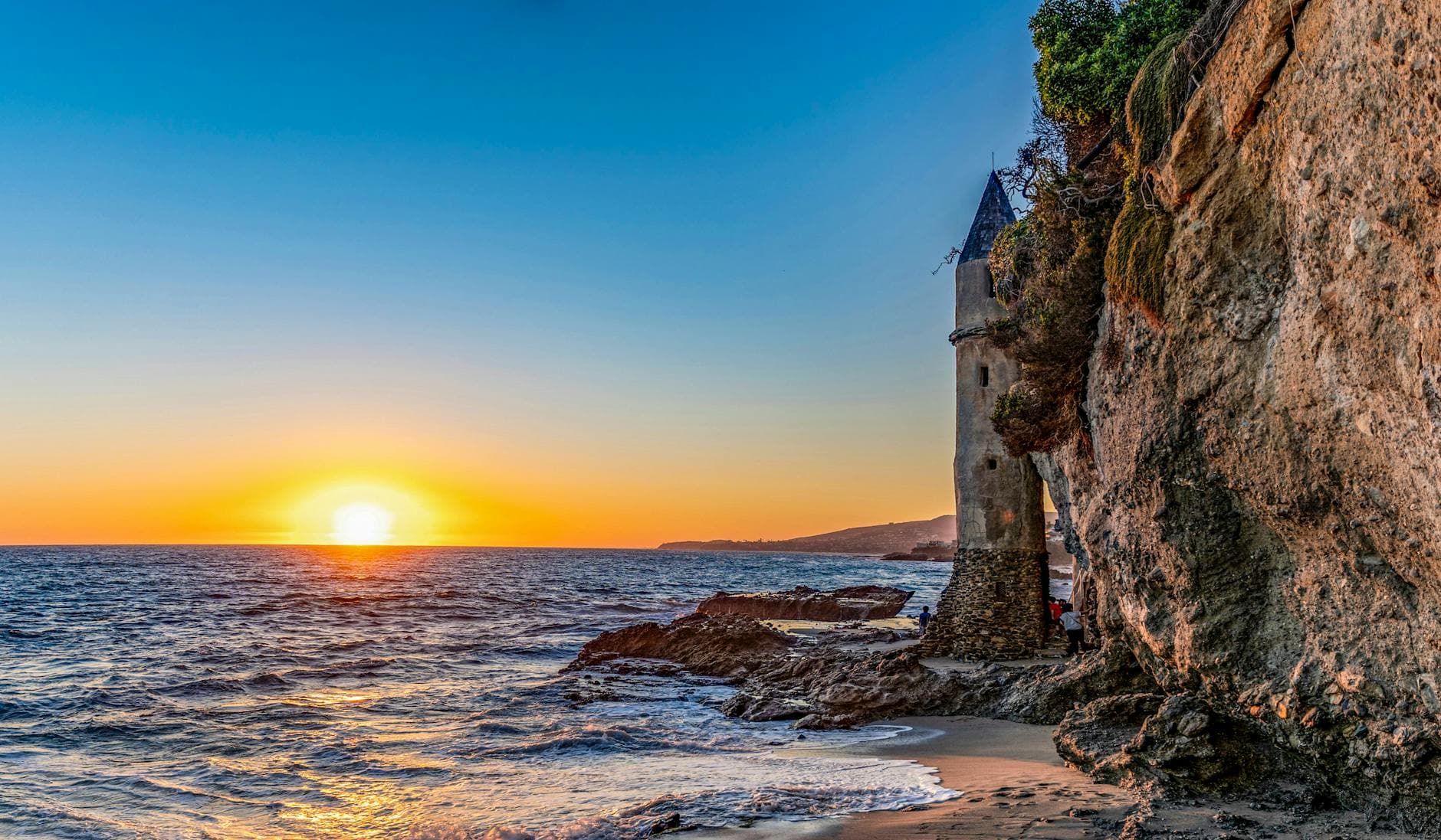 Witness the enchanting Pirate Tower at Laguna Beach during a vibrant sunset.