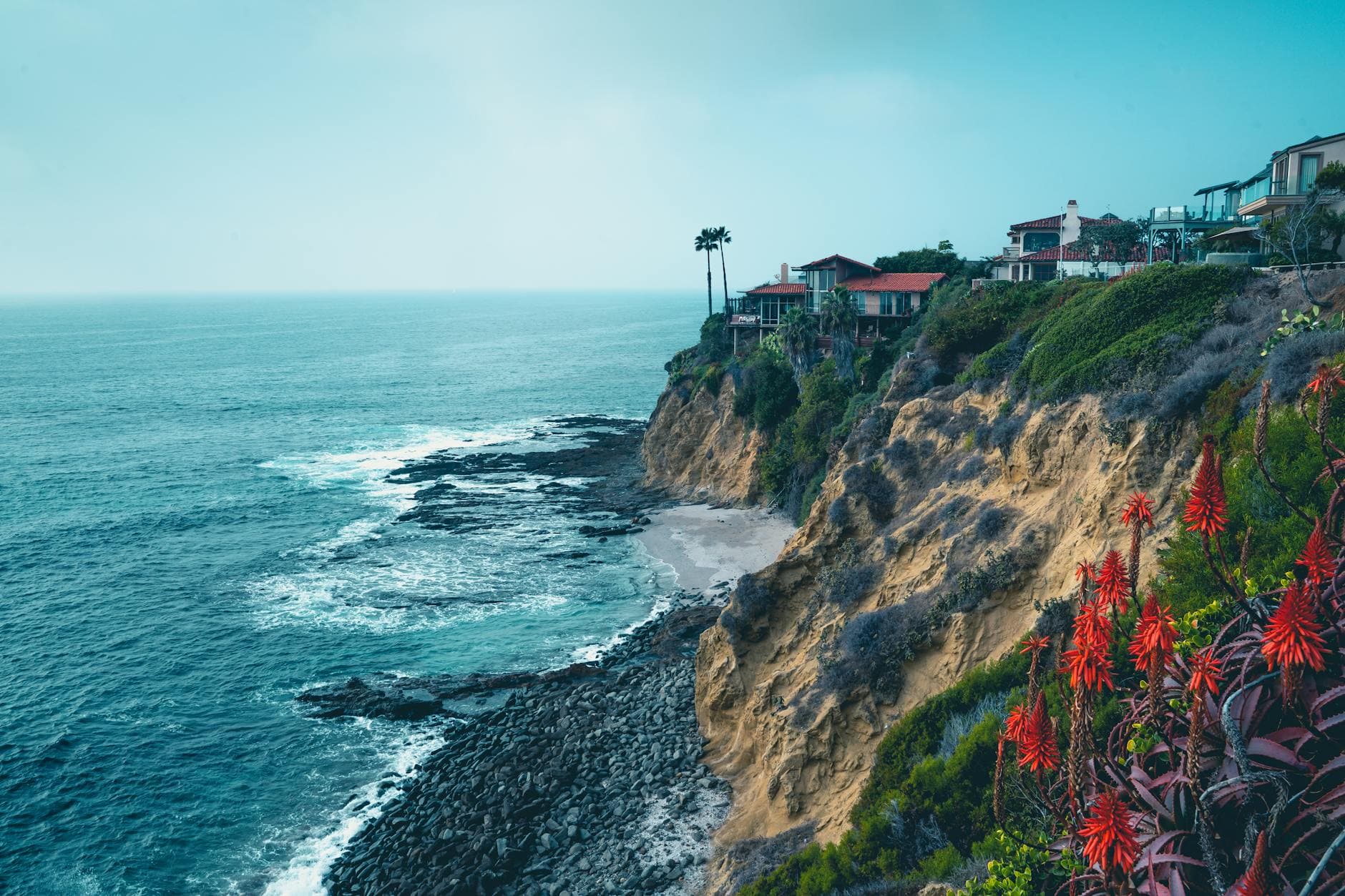 Stunning view of Laguna Beach cliffs with ocean waves and coastal homes under a clear sky.