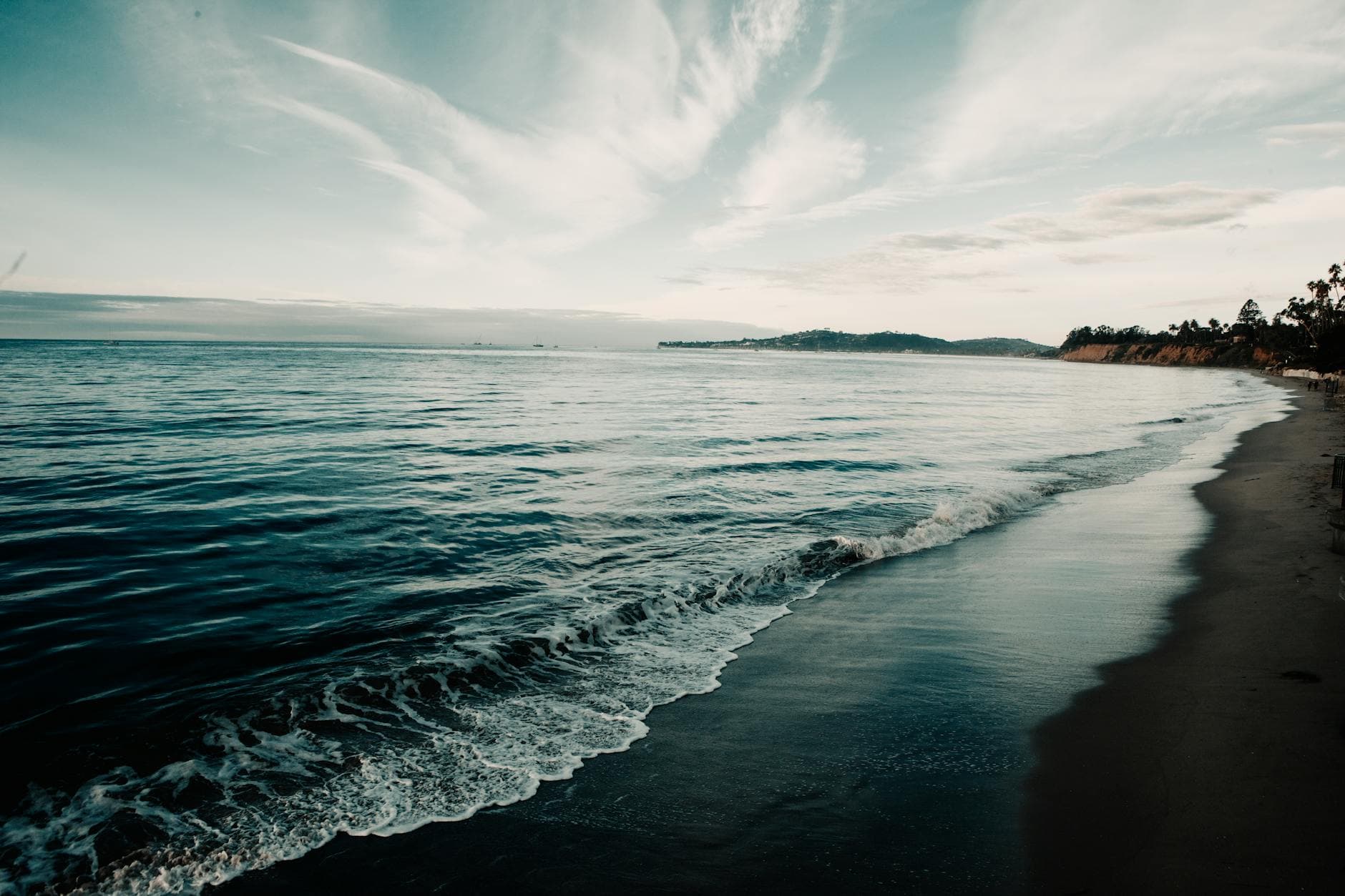 Serene view of Montecito Beach in California with gentle waves under a dramatic sky.