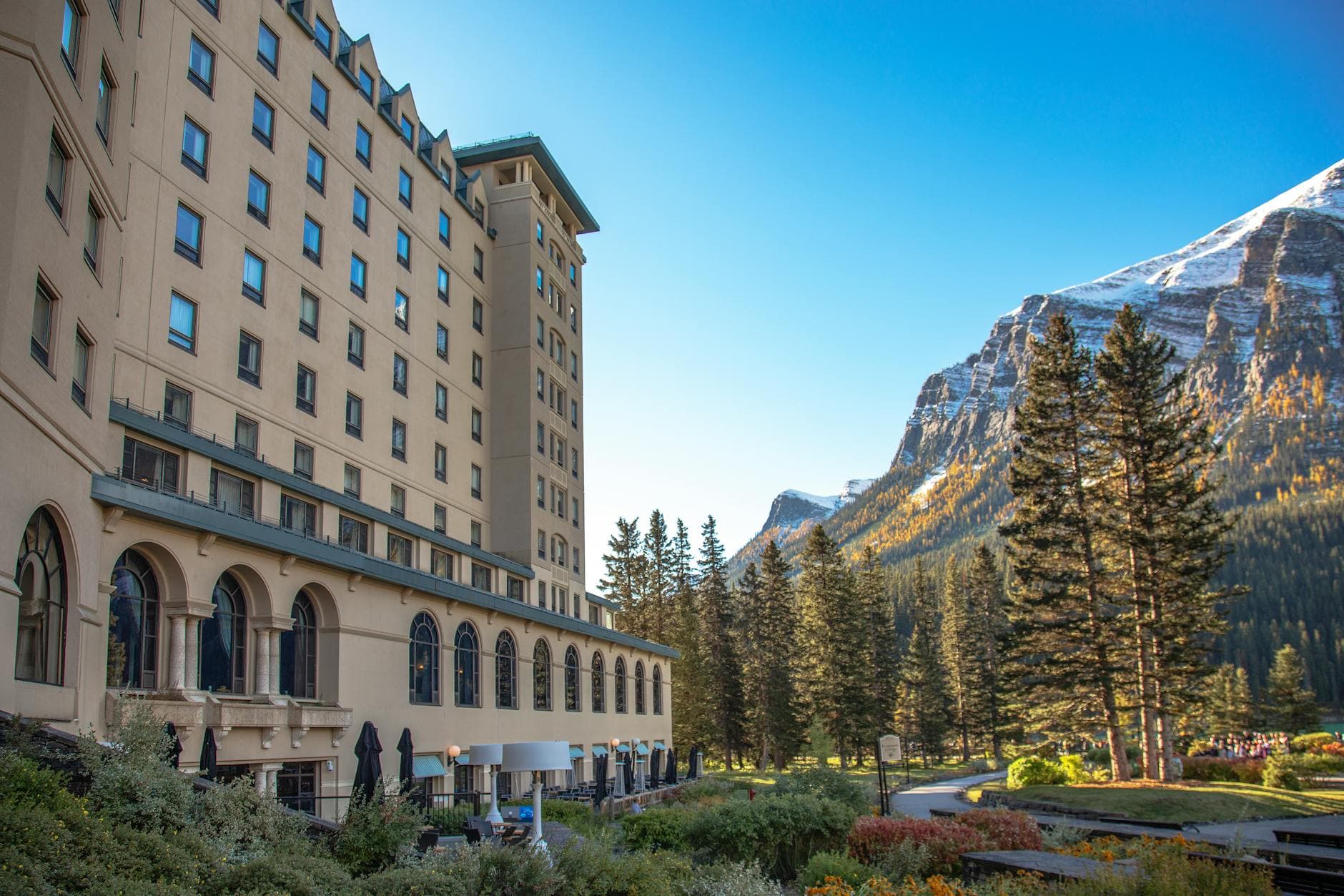 Stunning view of Chateau Lake Louise with snow-capped mountains and lush forest in Alberta, Canada.