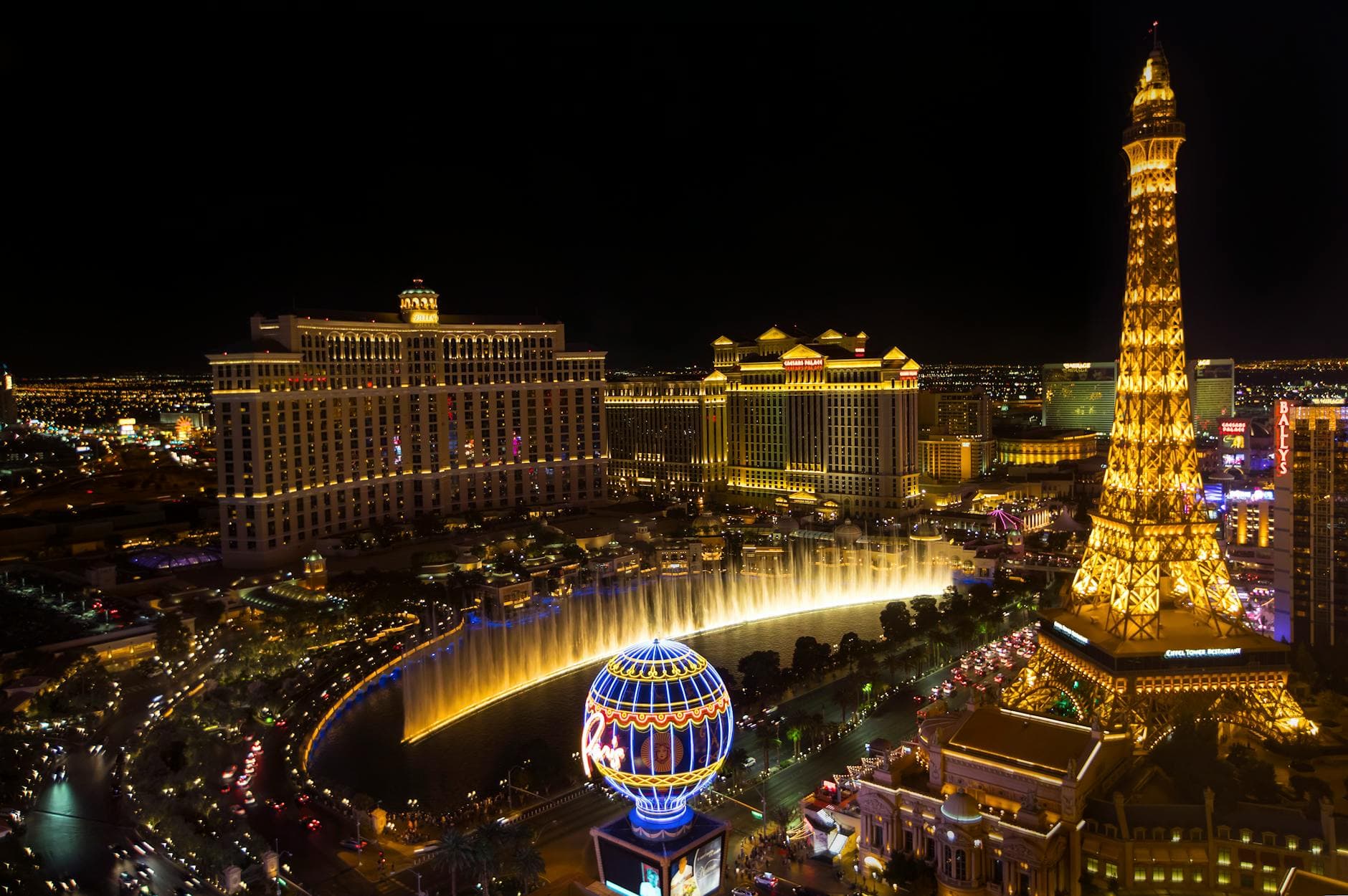 Bright lights of Las Vegas Strip showcasing the iconic Eiffel Tower and Bellagio fountains at night.