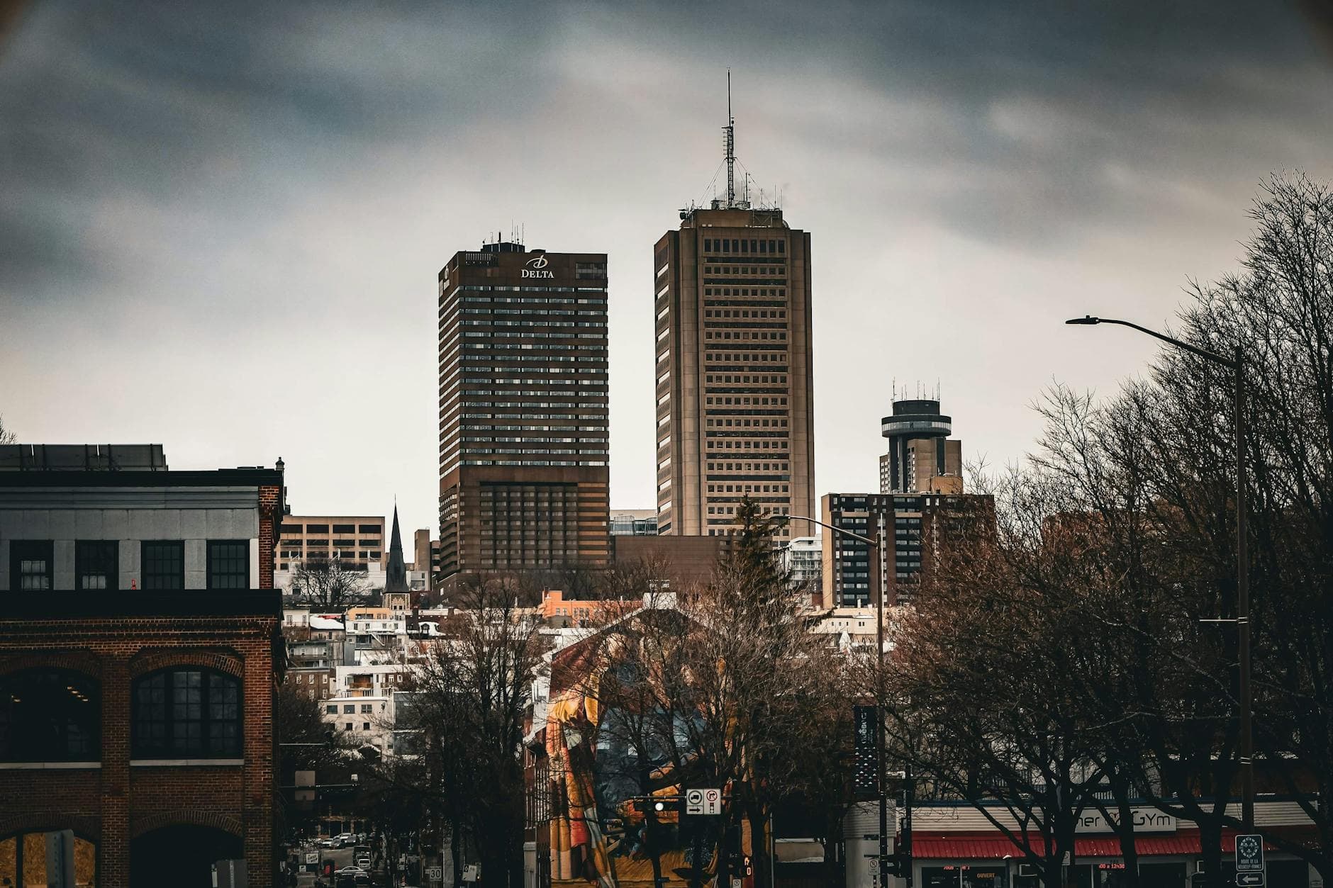 A modern urban skyline in Québec City, featuring prominent skyscrapers under a cloudy sky.
