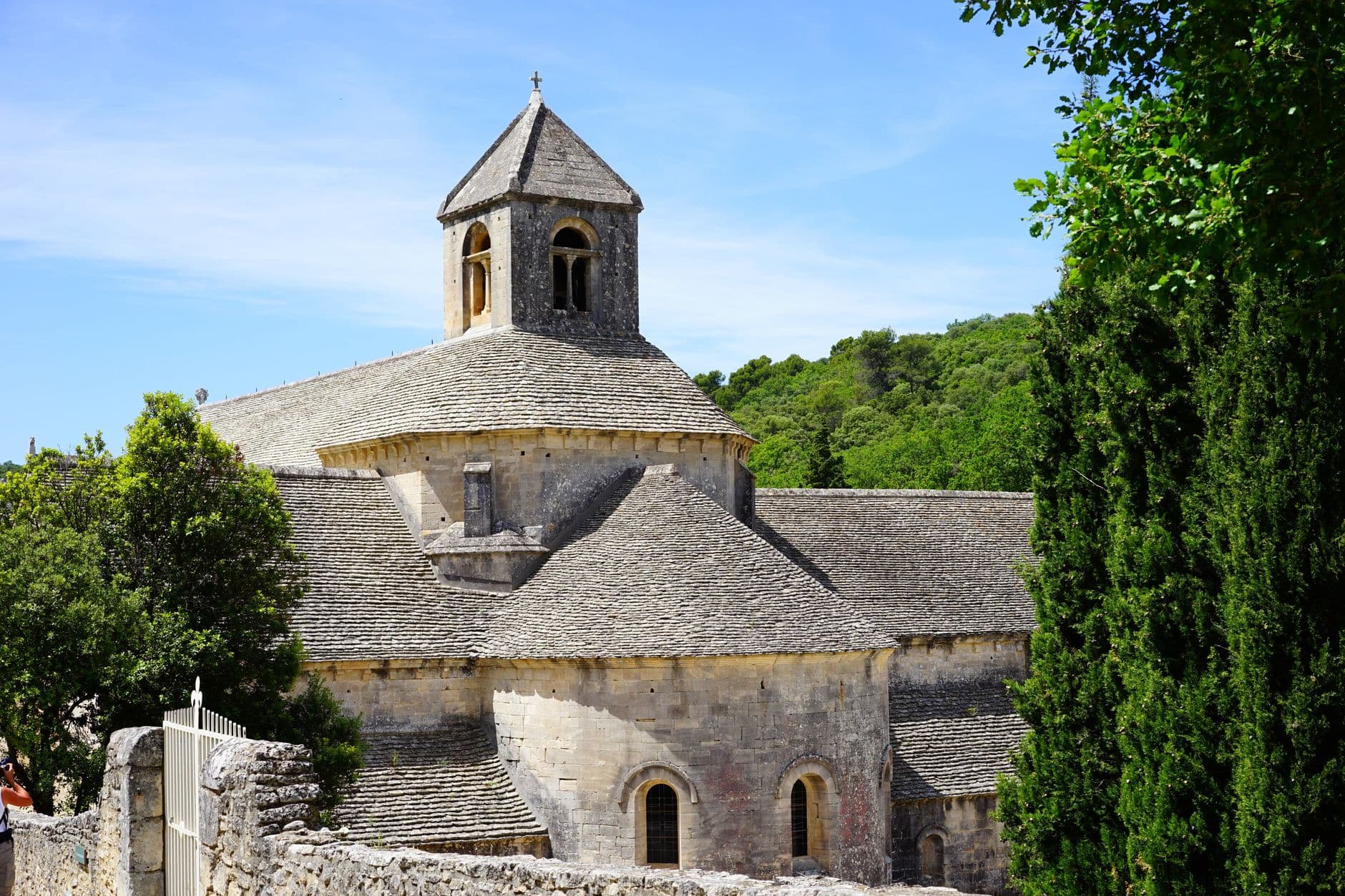 A picturesque view of the historic Sénanque Abbey surrounded by lush greenery and summer sunshine.