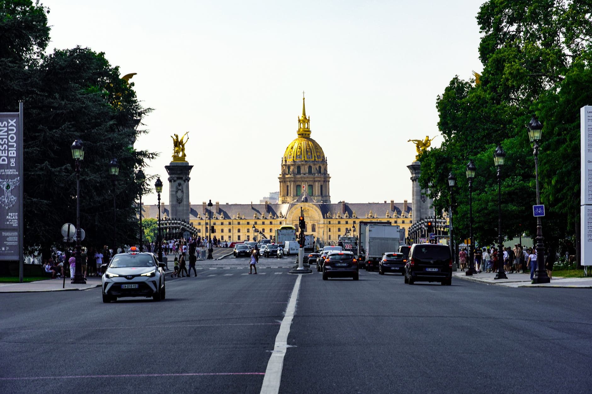 Street scene with cars and the iconic Les Invalides dome in Paris.