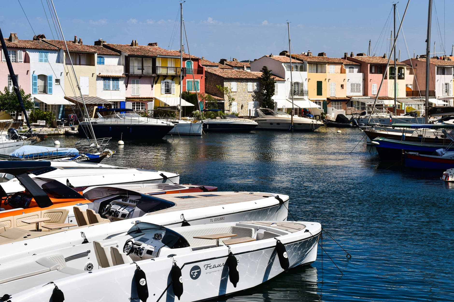 Scenic view of Port Grimaud marina with vibrant houses and luxury boats on a sunny day.