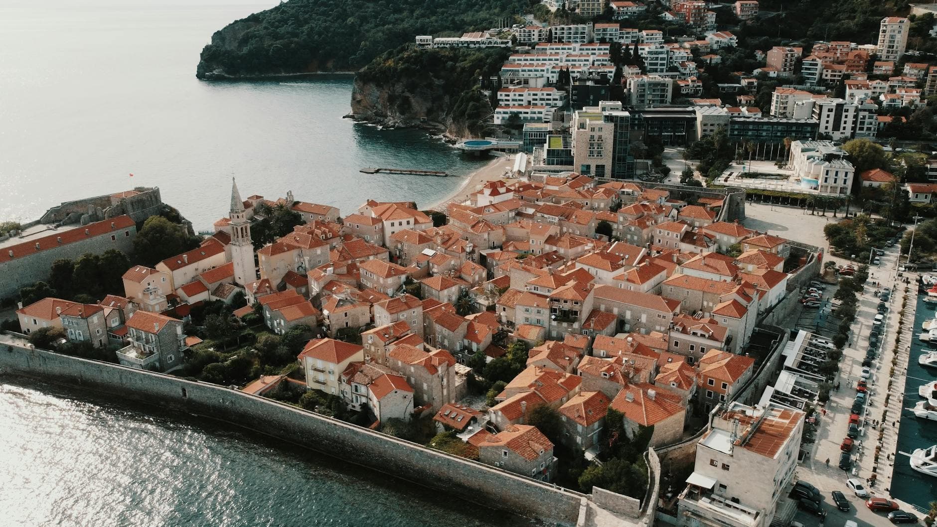 Experience the stunning aerial view of Budva's historic Old Town with its distinctive red roofs on the Adriatic coast.