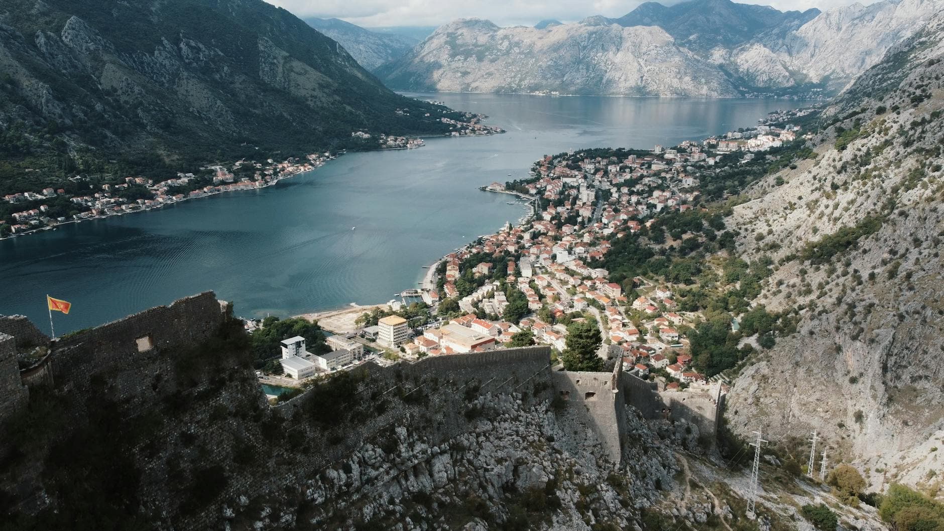 A breathtaking aerial view of Kotor Bay with ancient castle ruins in Montenegro, surrounded by majestic mountains.