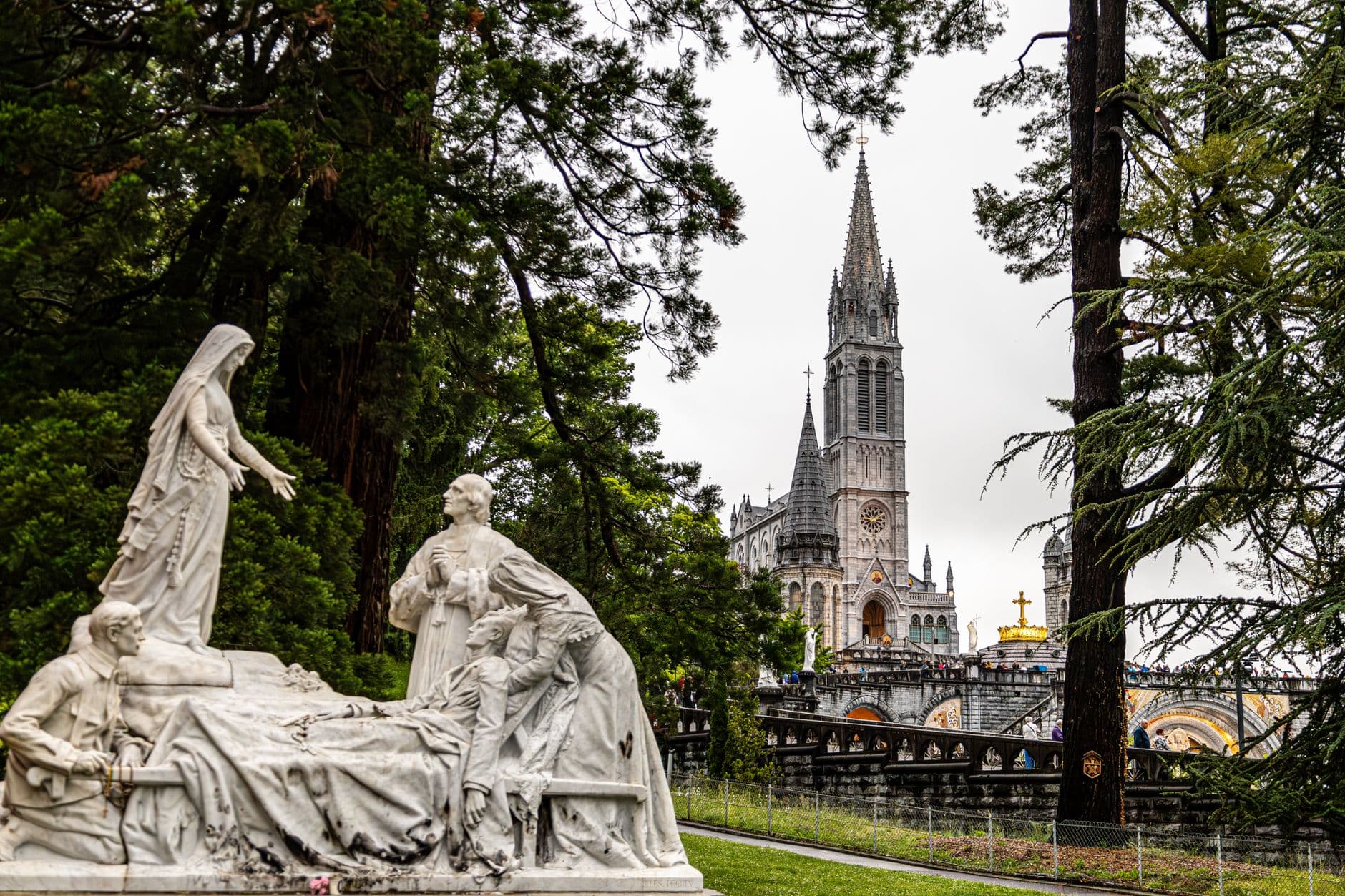 View of Basilica of Lourdes with a detailed marble sculpture in the foreground creating a serene historical scene.
