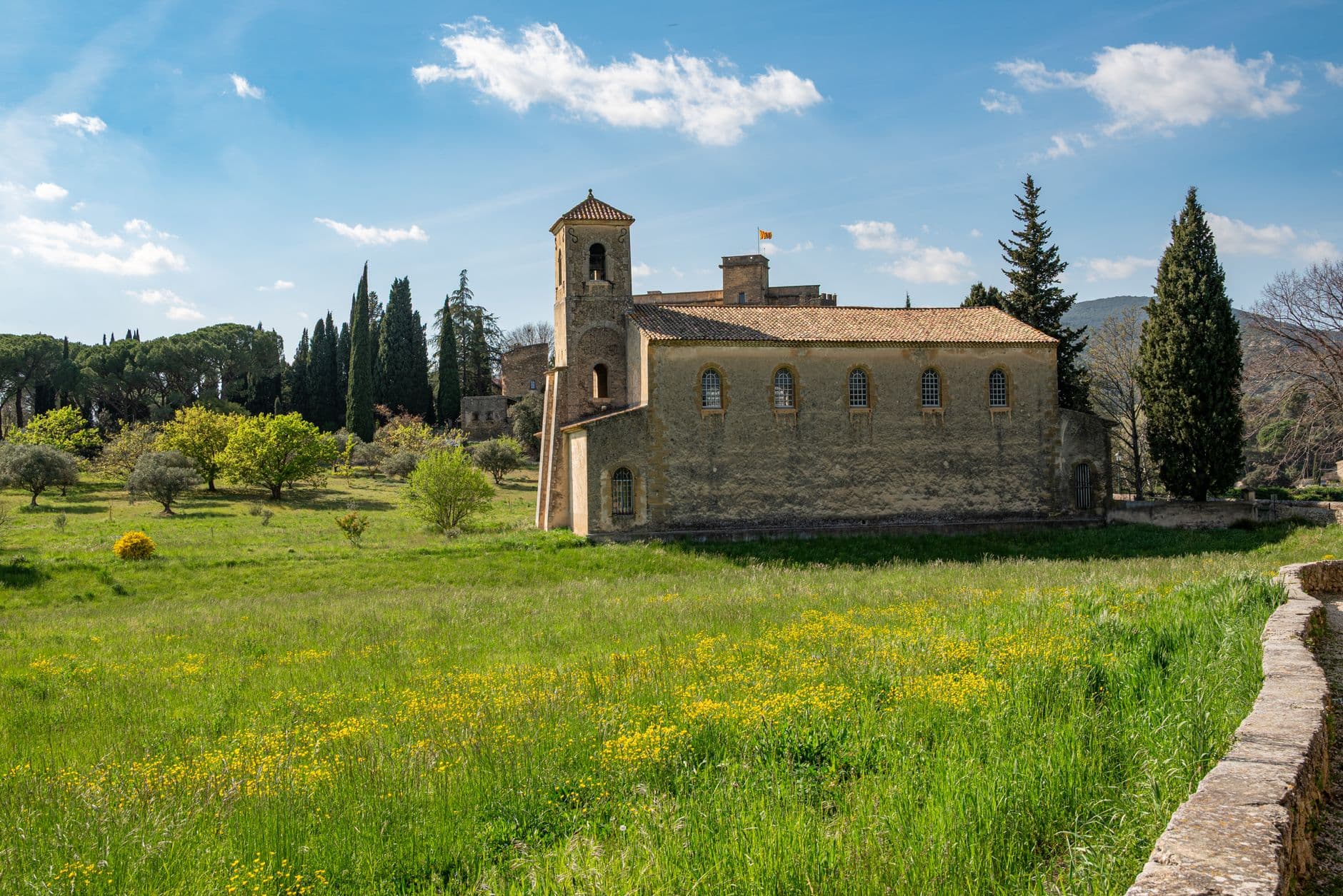 Charming old church in Lourmarin, France, amidst lush greenery and bright spring flowers.