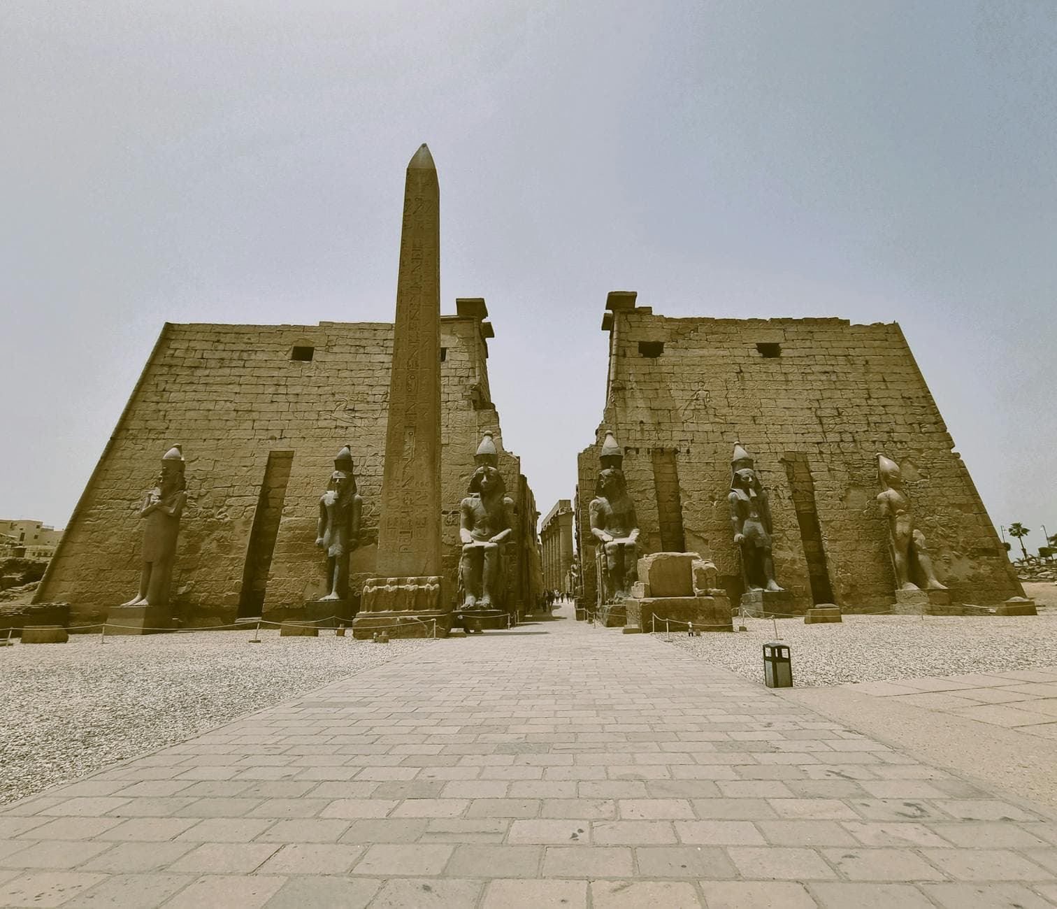 A captivating view of the ancient Luxor Temple with towering obelisks and statues under a clear sky.