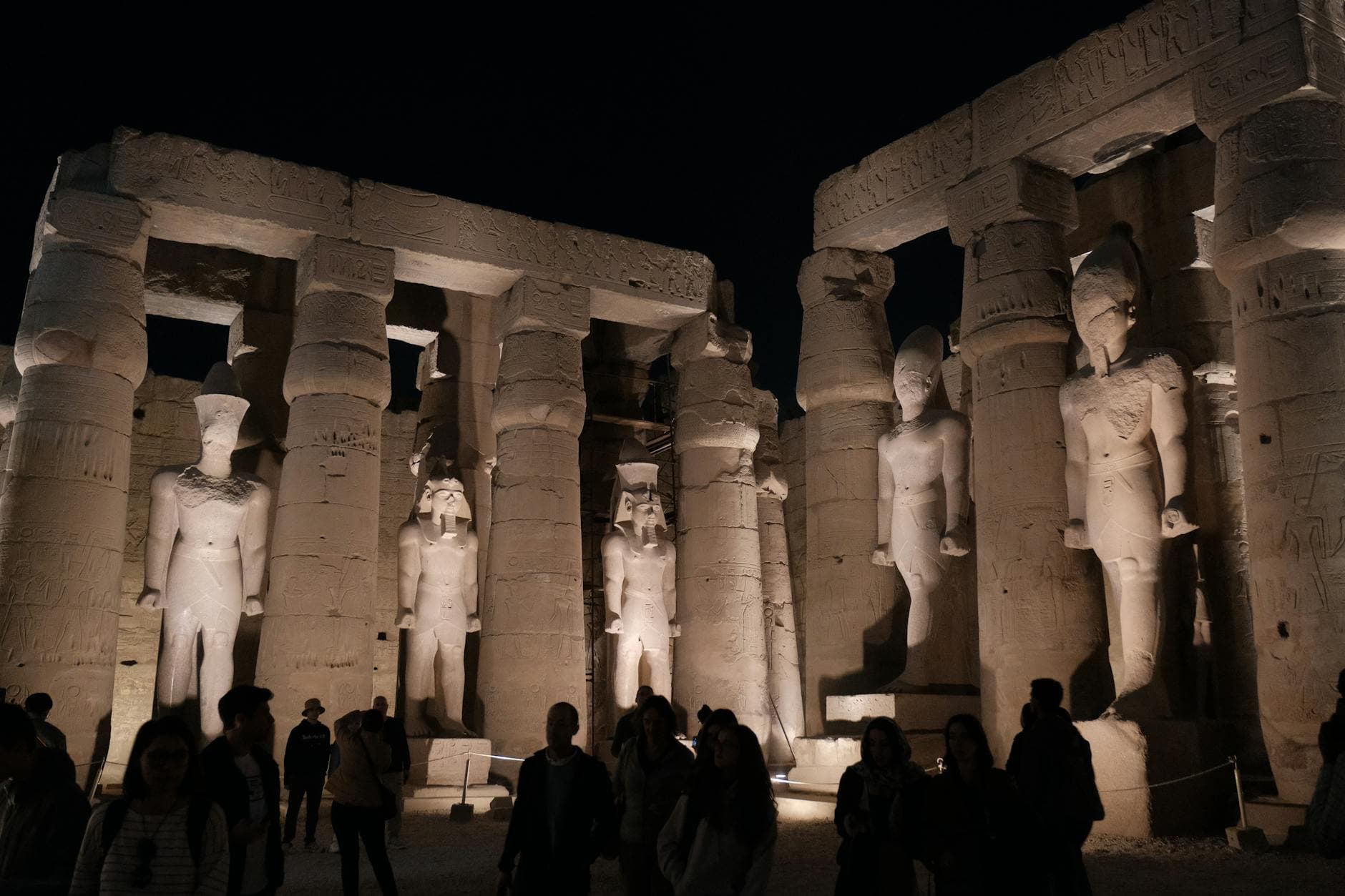 Illuminated statues at Luxor Temple under the night sky, showcasing Egyptian history.