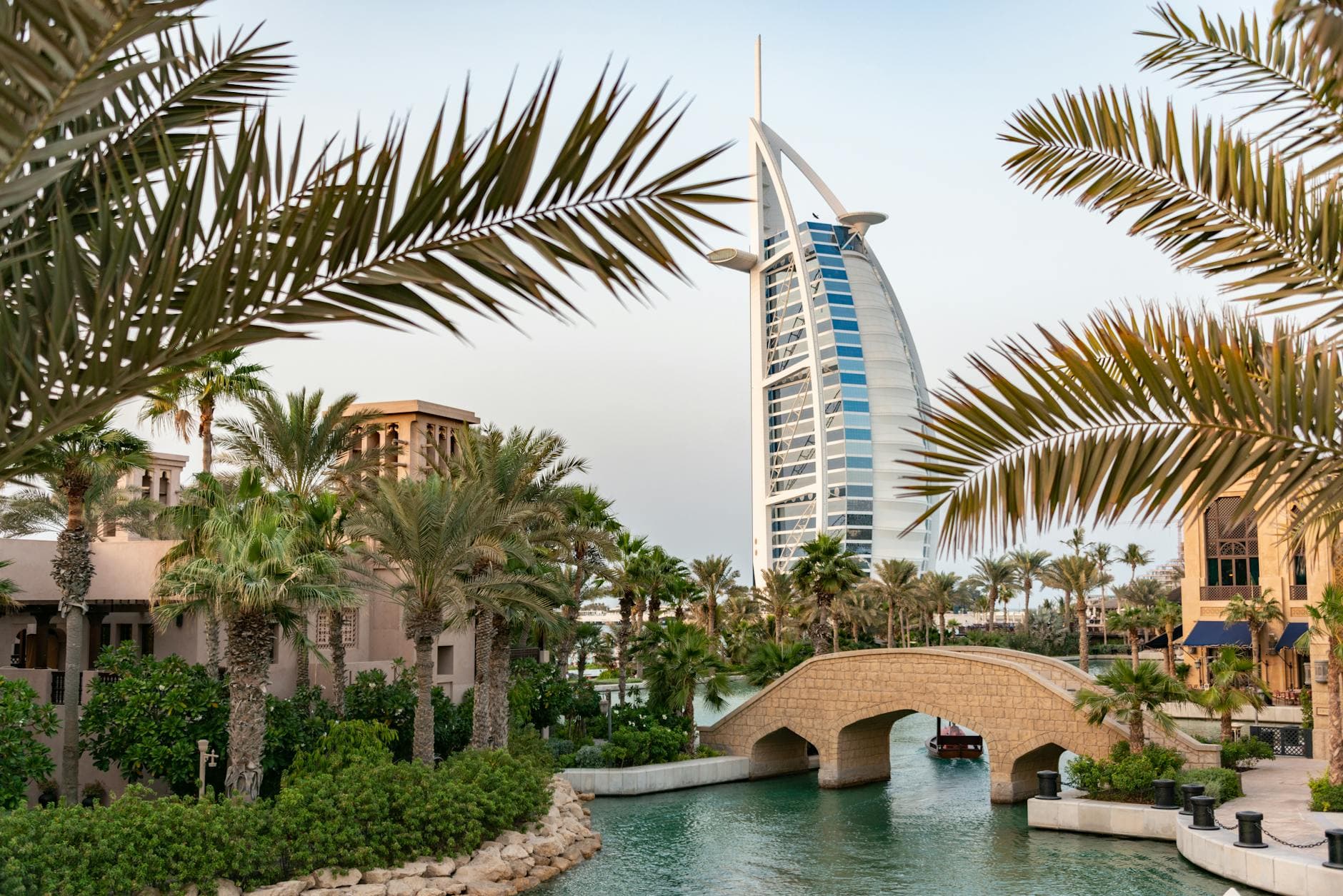 Scenic view of Burj Al Arab with surrounding palm trees and bridge in Dubai, UAE.