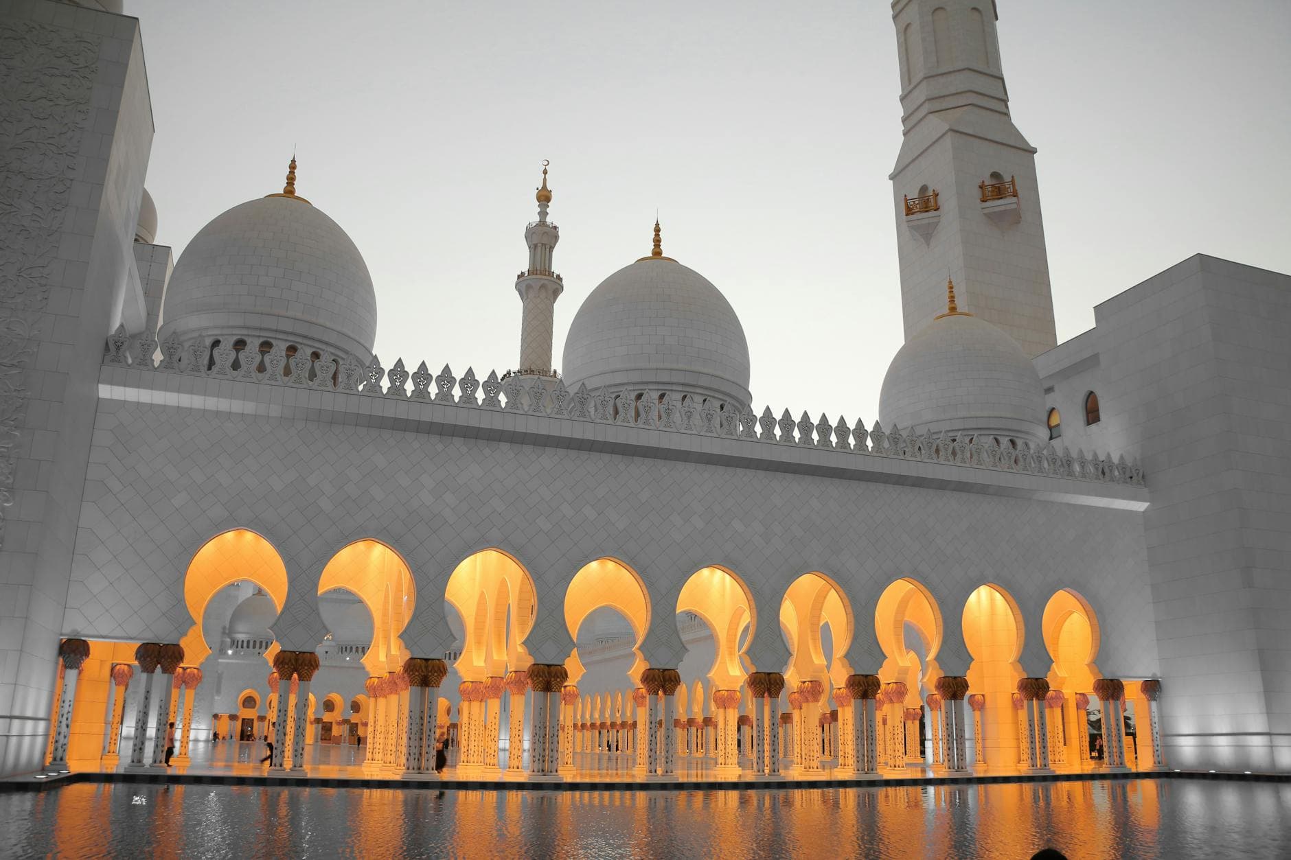 Stunning view of Sheikh Zayed Mosque with illuminated arches and domes during dusk.