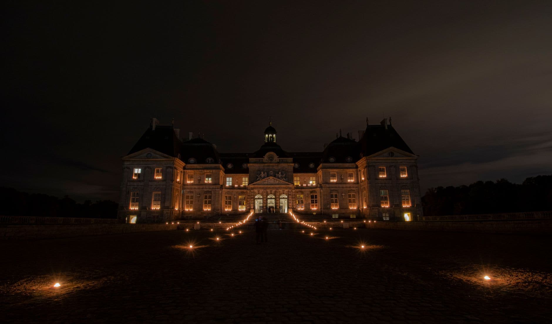 Gorgeous night view of Vaux-le-Vicomte Castle in Maincy, France, with illuminated pathways.